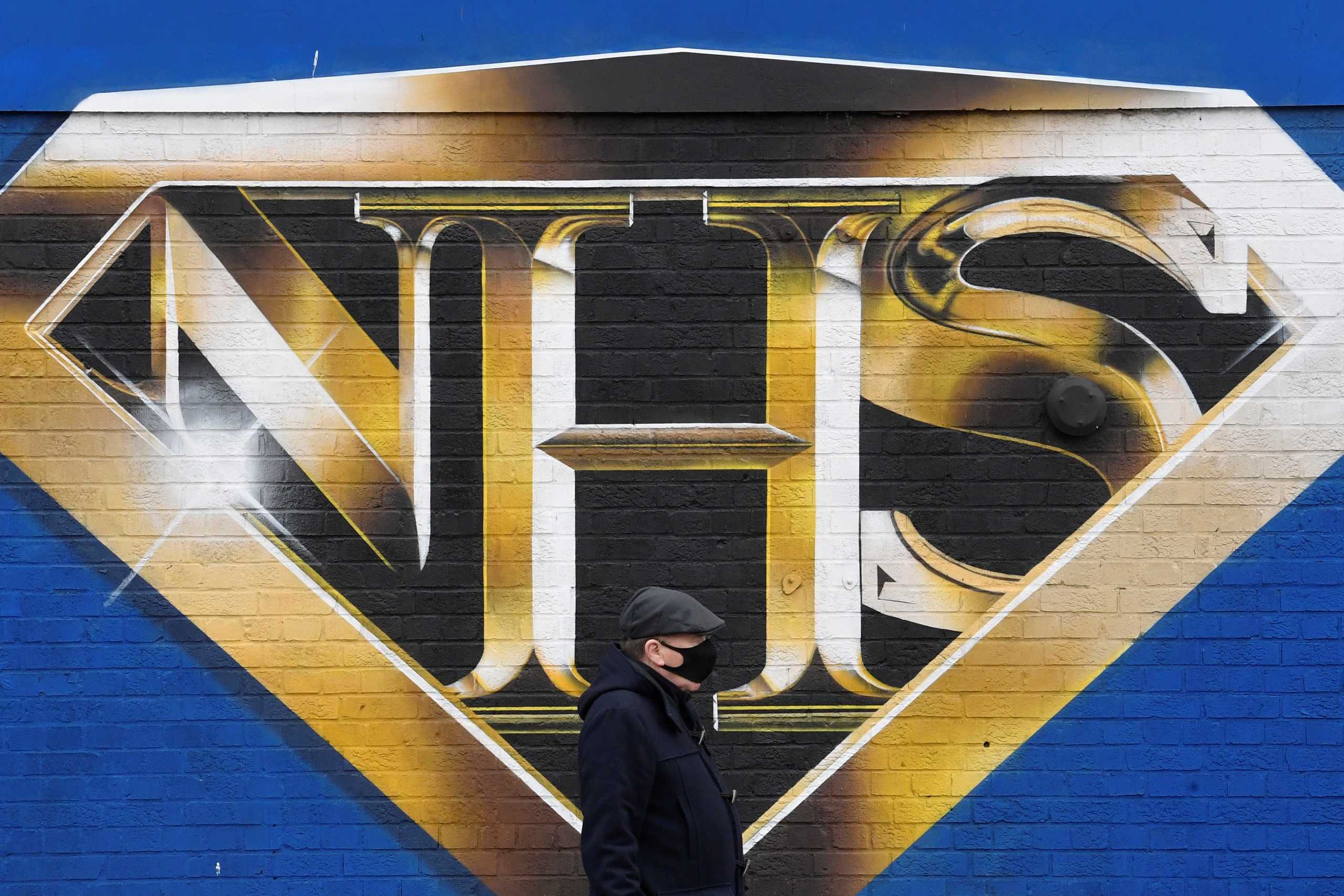 A man wearing a protective face mask walks past a mural praising the NHS (National Health Service) amidst the continuation of the coronavirus disease (COVID-19) pandemic, London, Britain, March 5, 2021. REUTERS