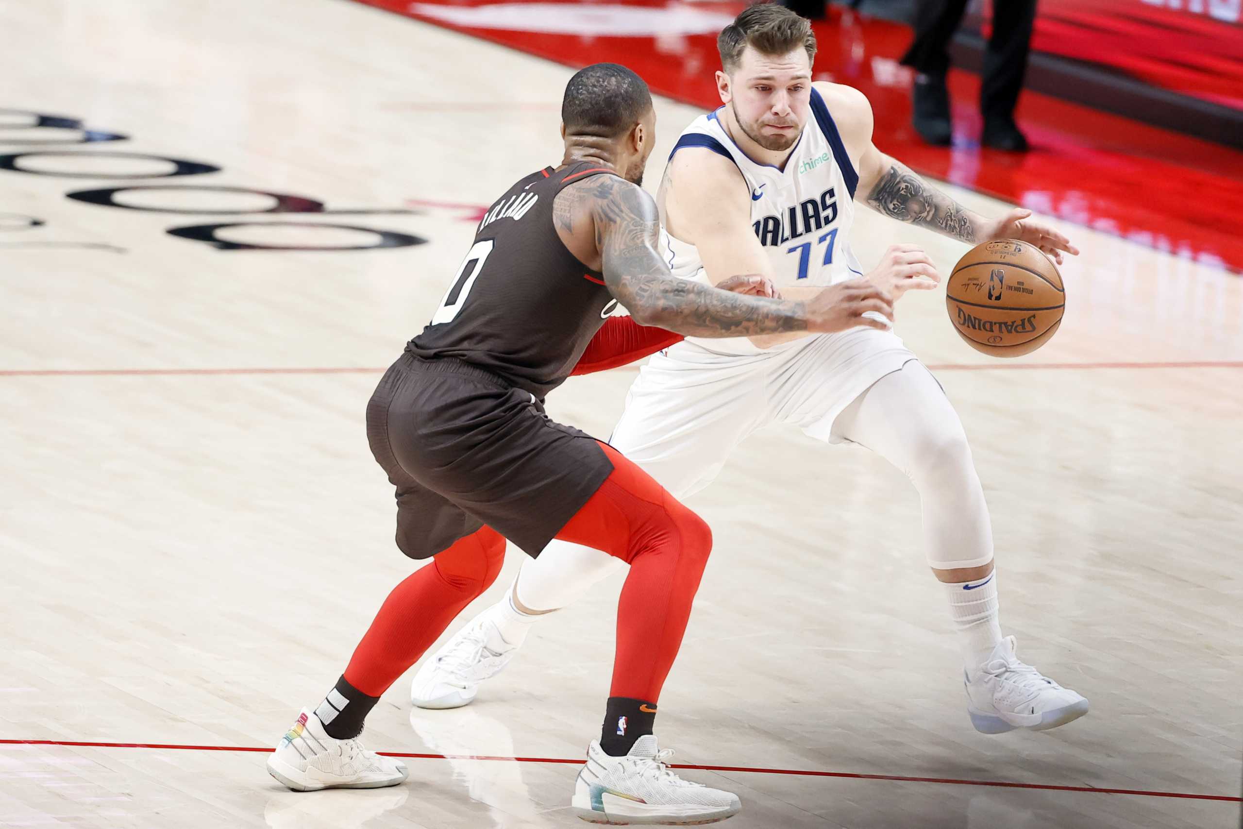 Mar 21, 2021; Portland, Oregon, USA; Dallas Mavericks point guard Luka Doncic (77) dribbles the ball as Portland Trail Blazers point guard Damian Lillard (L) defends during the first half at Moda Center. Mandatory Credit: Soobum Im-USA TODAY Sports
