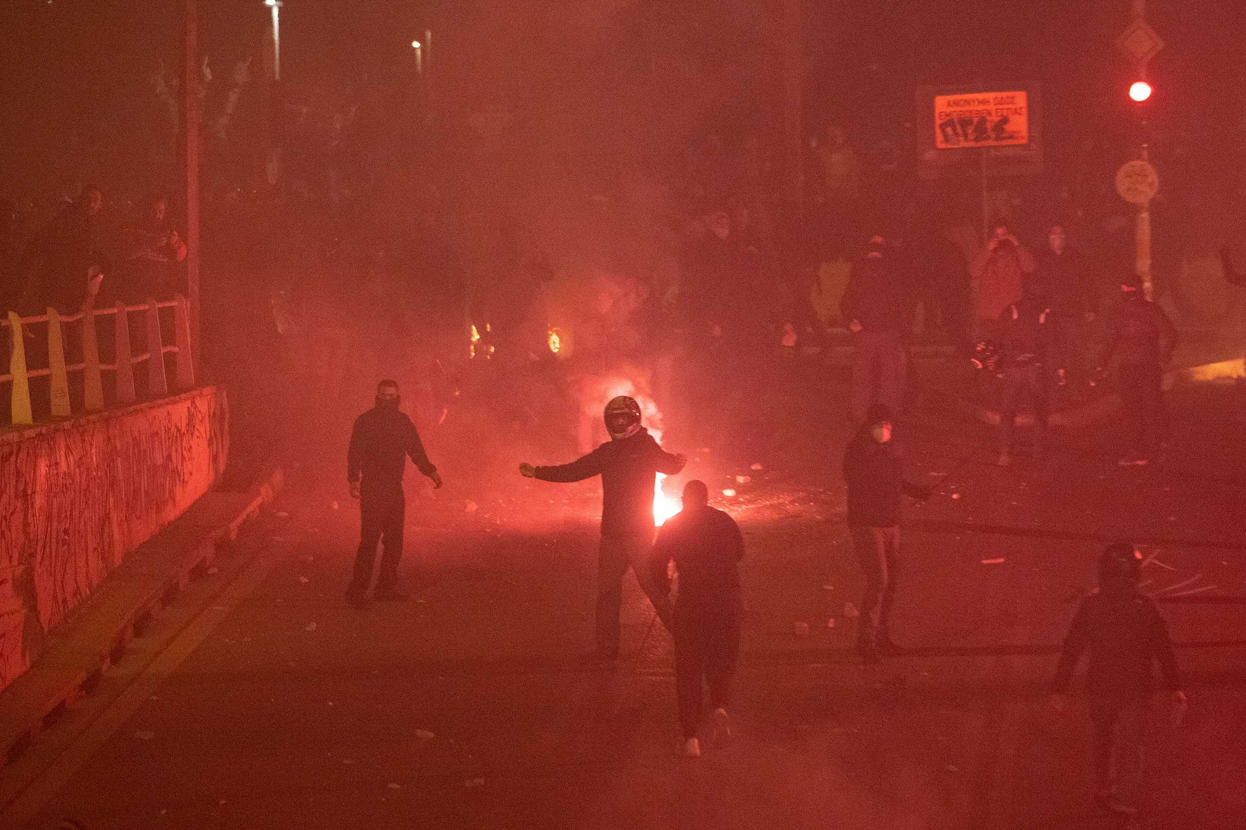 Flares burn near protesters, as they clash with police officers during a demonstration against a police crackdown on gatherings, in Athens, Greece, March 9, 2021. REUTERS