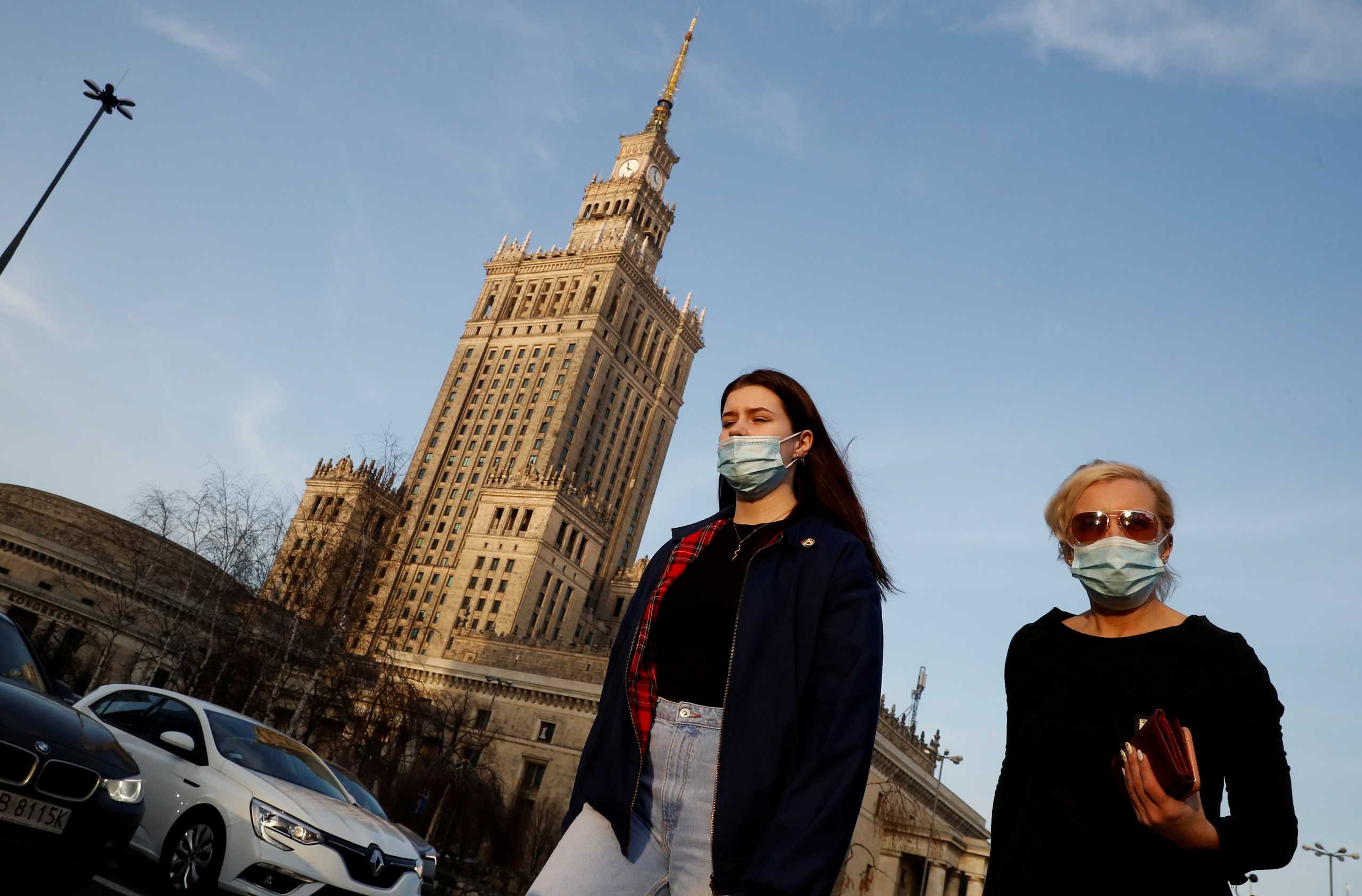 FILE PHOTO: People wearing protective masks amid the outbreak of coronavirus disease (COVID-19) walk in front of the Palace of Culture and Science in the centre of Warsaw, Poland February 24, 2021. REUTERS