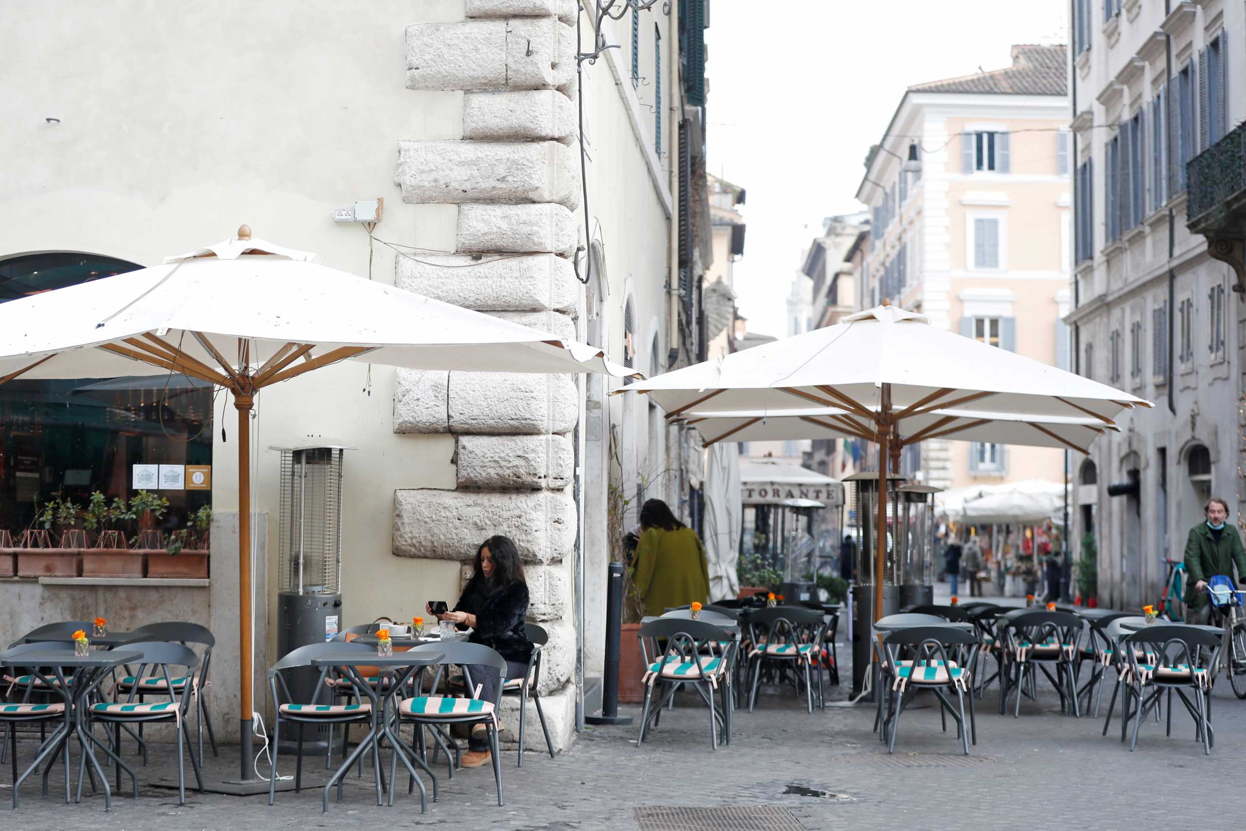 FILE PHOTO: A woman sits at a cafe at Campo de' Fiori after the coronavirus disease (COVID-19) restrictions were eased in Lazio region, Rome, Italy, February 1, 2021. REUTERS