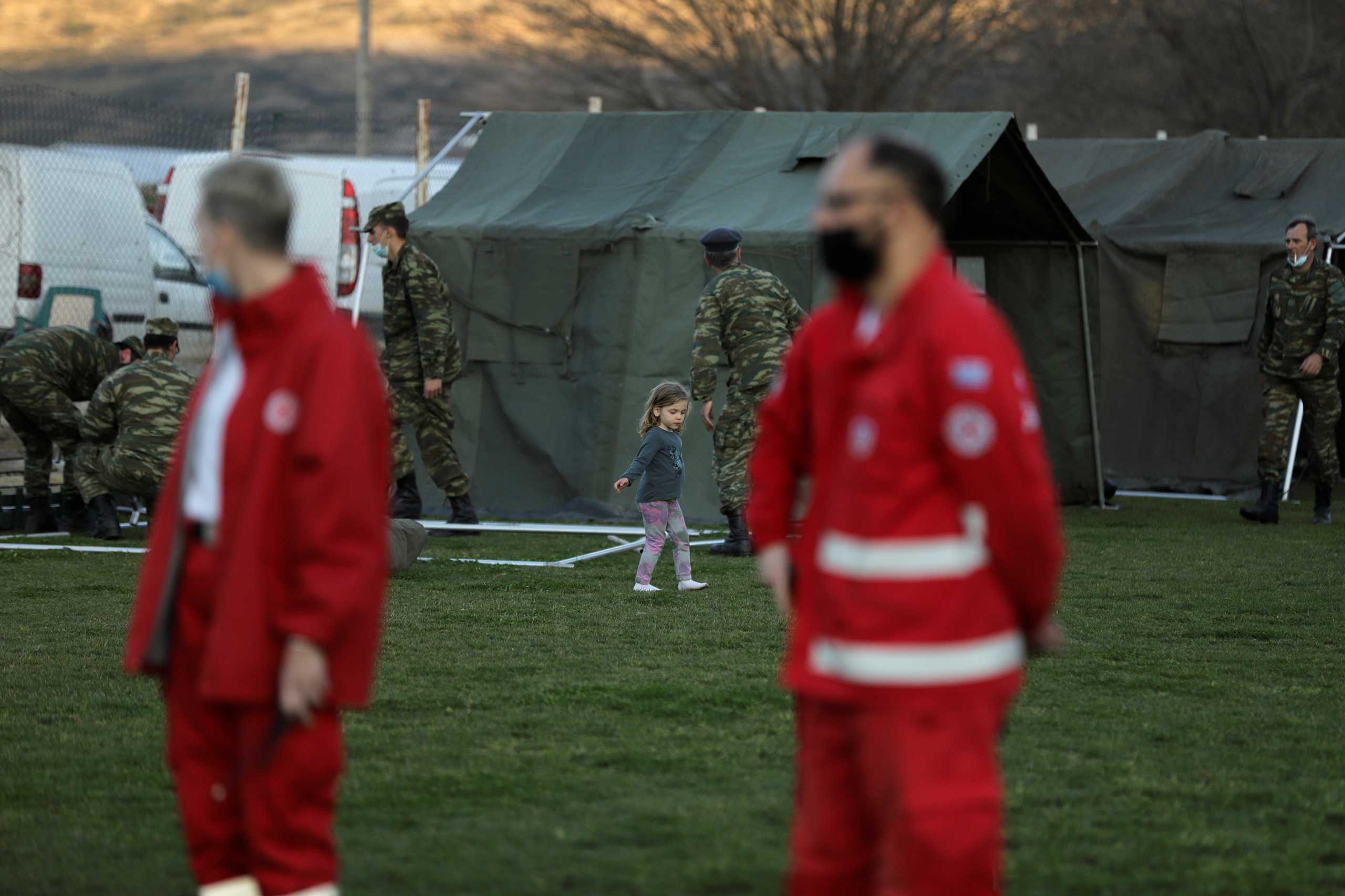 A girl makes her way next to soldiers setting up tents in a soccer stadium, following a quake in the village of Damasi, in central Greece, March 3, 2021. REUTERS