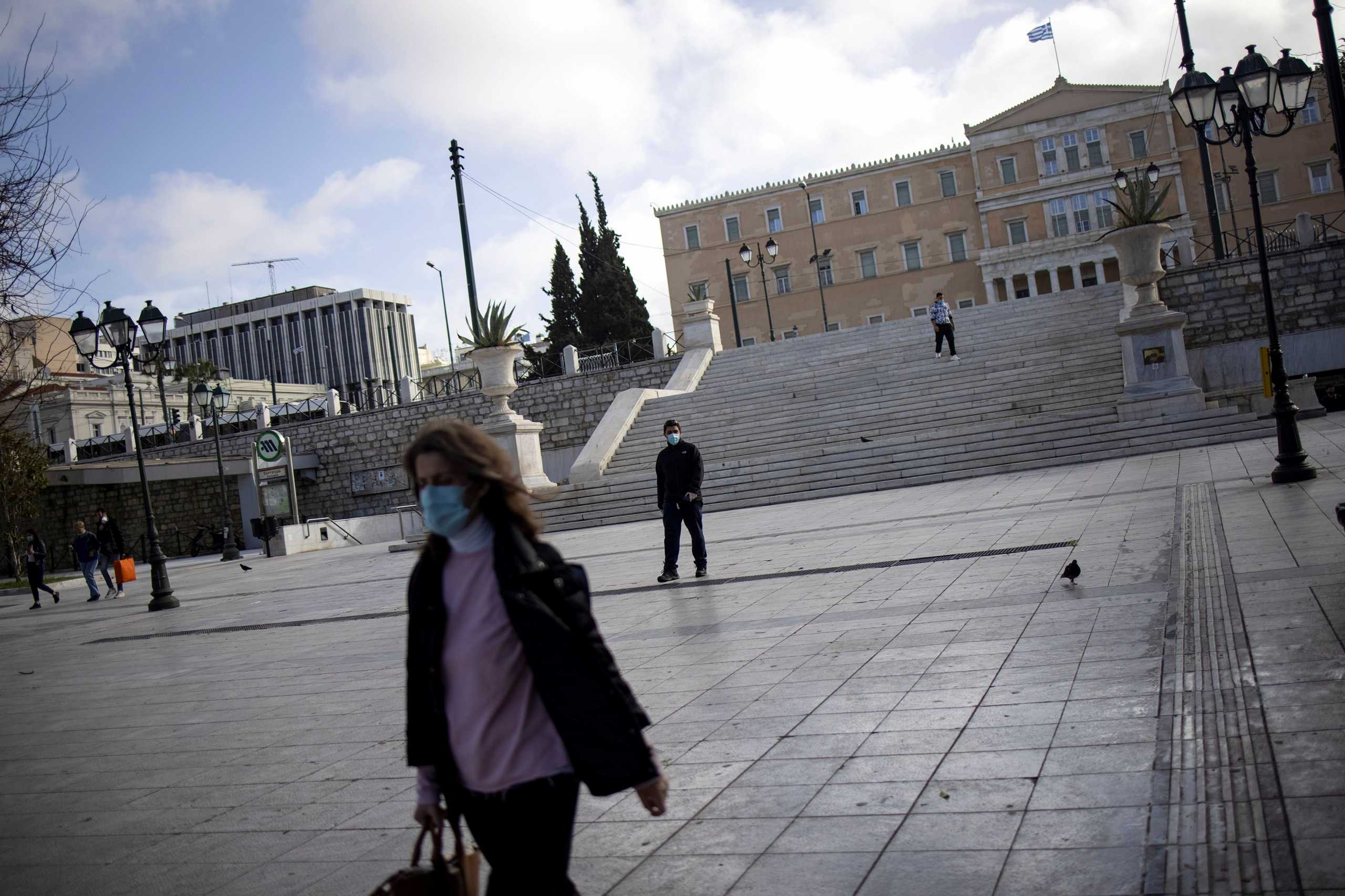 FILE PHOTO: People wearing protective masks walk on Syntagma square, after the Greek government imposed stricter lockdown measures to curb the spread of the coronavirus disease (COVID-19) pandemic, in Athens, Greece, February 11, 2021. REUTERS