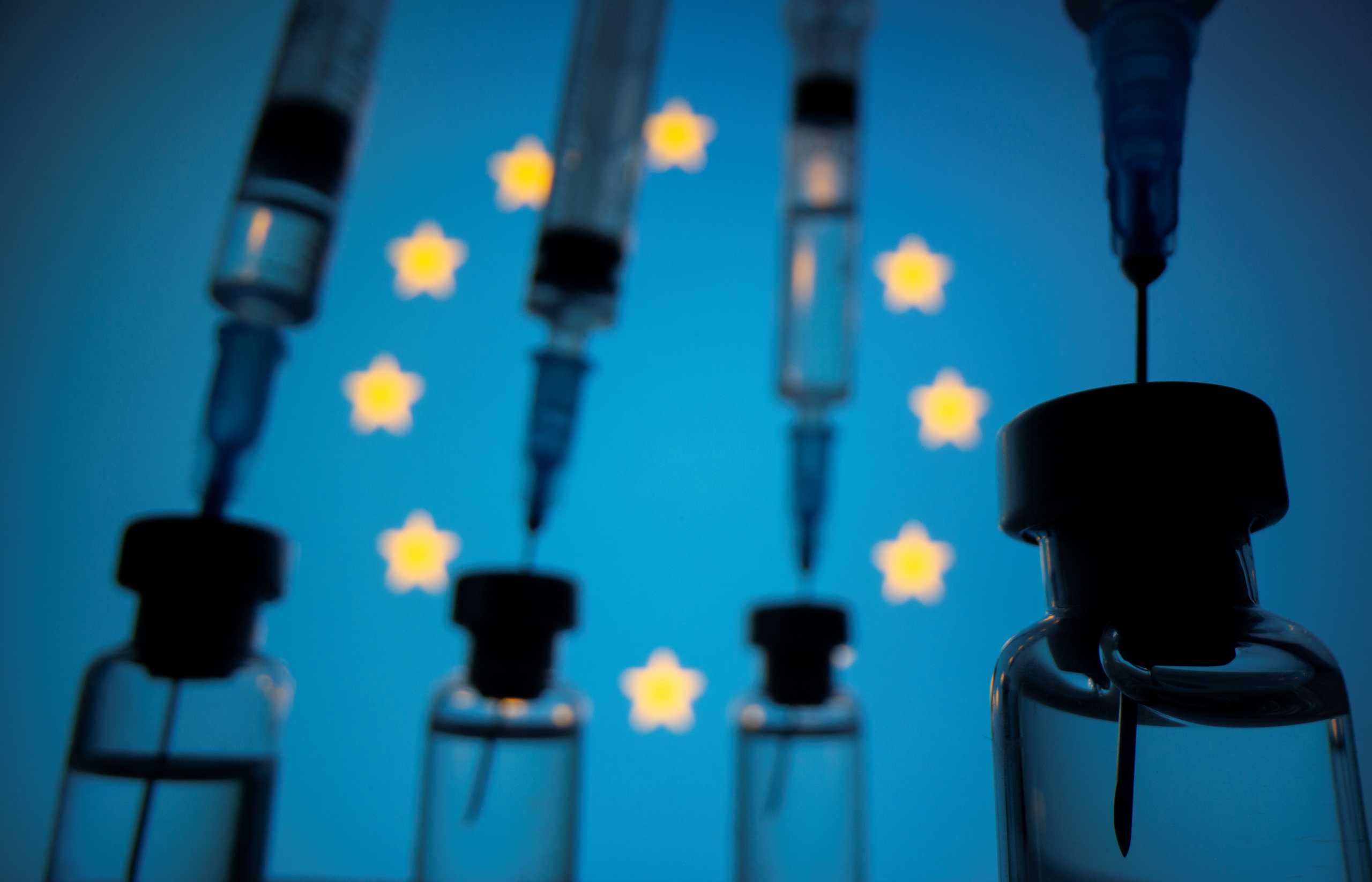 Vials and syringes are seen in front of displayed EU flag in this illustration photo taken March 16, 2021. Picture taken March 16, 2021. REUTERS