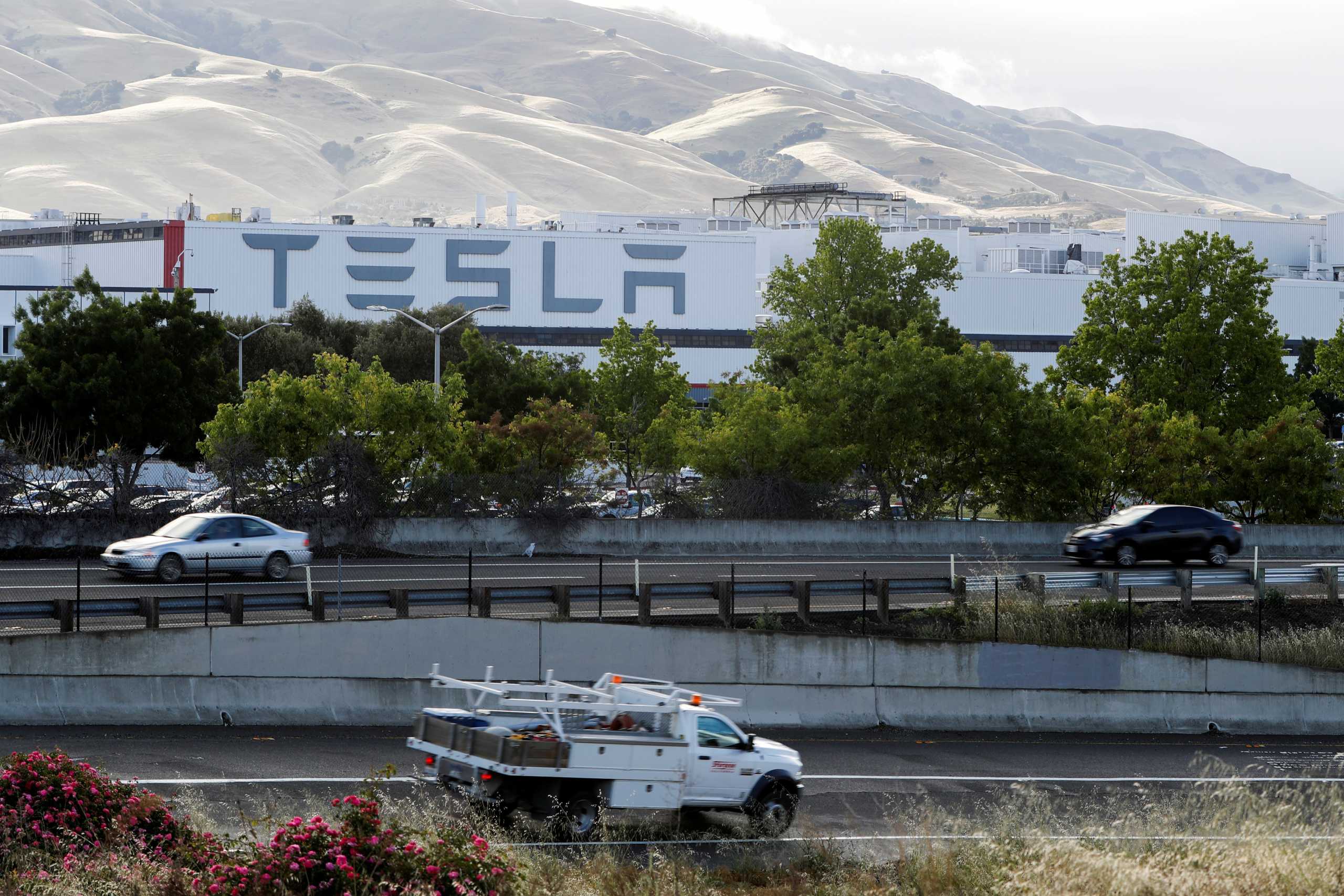 FILE PHOTO: Motorists drive past Tesla's primary vehicle factory after CEO Elon Musk announced he was defying local officials' restrictions against the spread of the coronavirus disease (COVID-19) by reopening the plant in Fremont, California, U.S. May 12, 2020. REUTERS