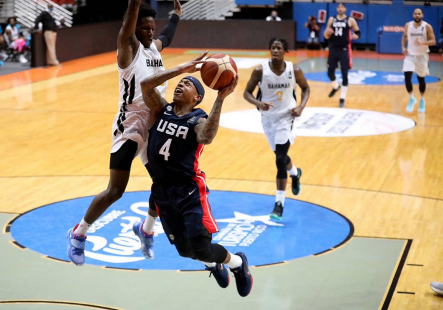 epa09025041 A handout photo made available by the International Basketball Federation (FIBA) shows Isaiah Thomas (C) of the USA in action against Dominick Bridgewater (L) of the Bahamas during the group D FIBA Americup 2022 qualifying basketball game between the the Bahamas and the USA at the Roberto Clemente Coliseum in San Juan, Puerto Rico, 19 February 2021.  EPA