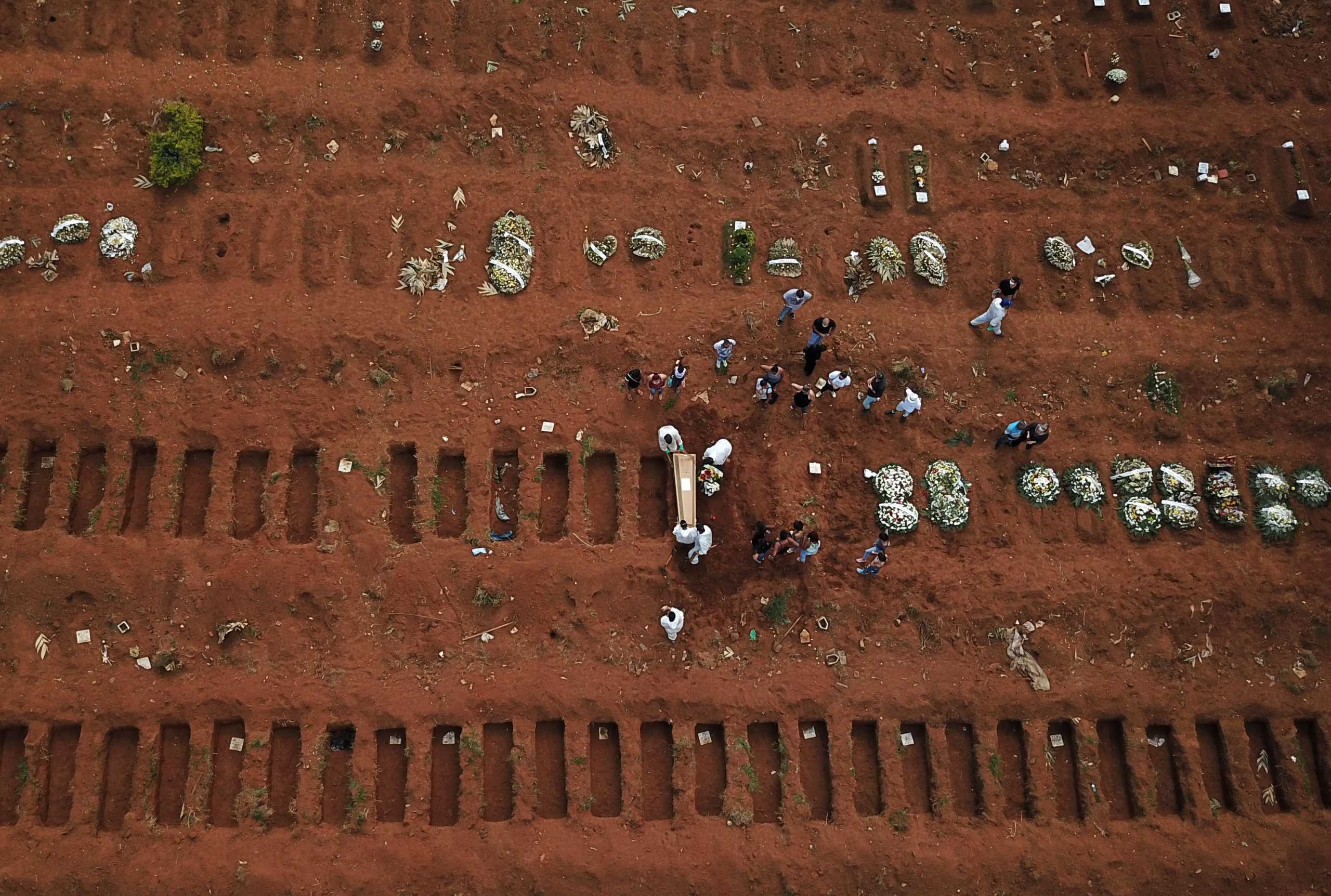 An aerial view shows gravediggers wearing protective suits carrying a coffin during burial of a person who died from the coronavirus disease (COVID-19) at Vila Formosa cemetery, in Sao Paulo, Brazil, March 23, 2021. Picture taken March 23, 2021. Picture taken with a drone. REUTERS