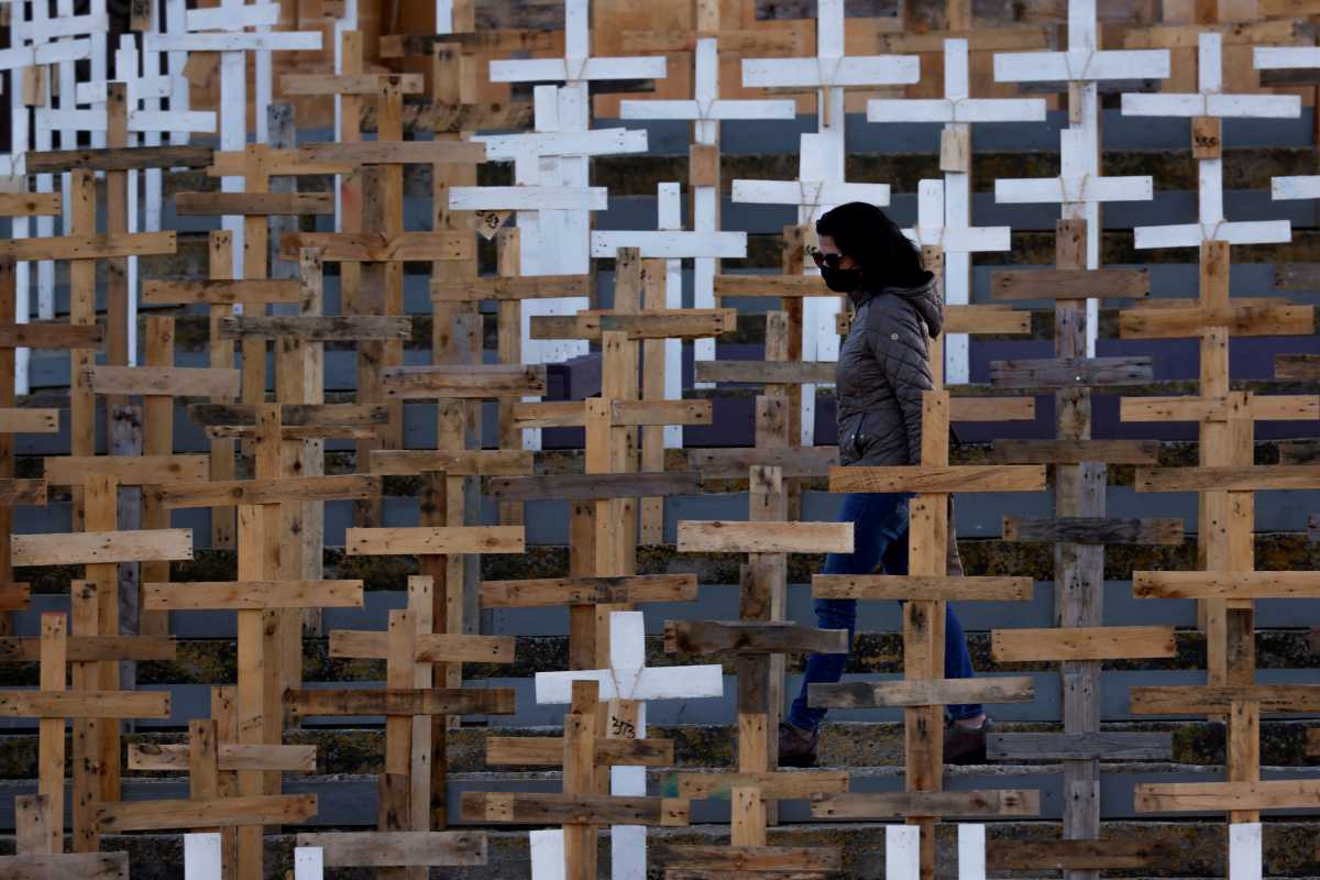 FILE PHOTO: A woman wearing a mask walks among hundreds of crosses set up in front of the Parish Church of Our Lady of Loreto to commemorate Holy Week and as a memorial to the victims of the coronavirus disease (COVID-19) pandemic, in the village of Ghajnsielem on the island of Gozo, Malta March 27, 2021. REUTERS