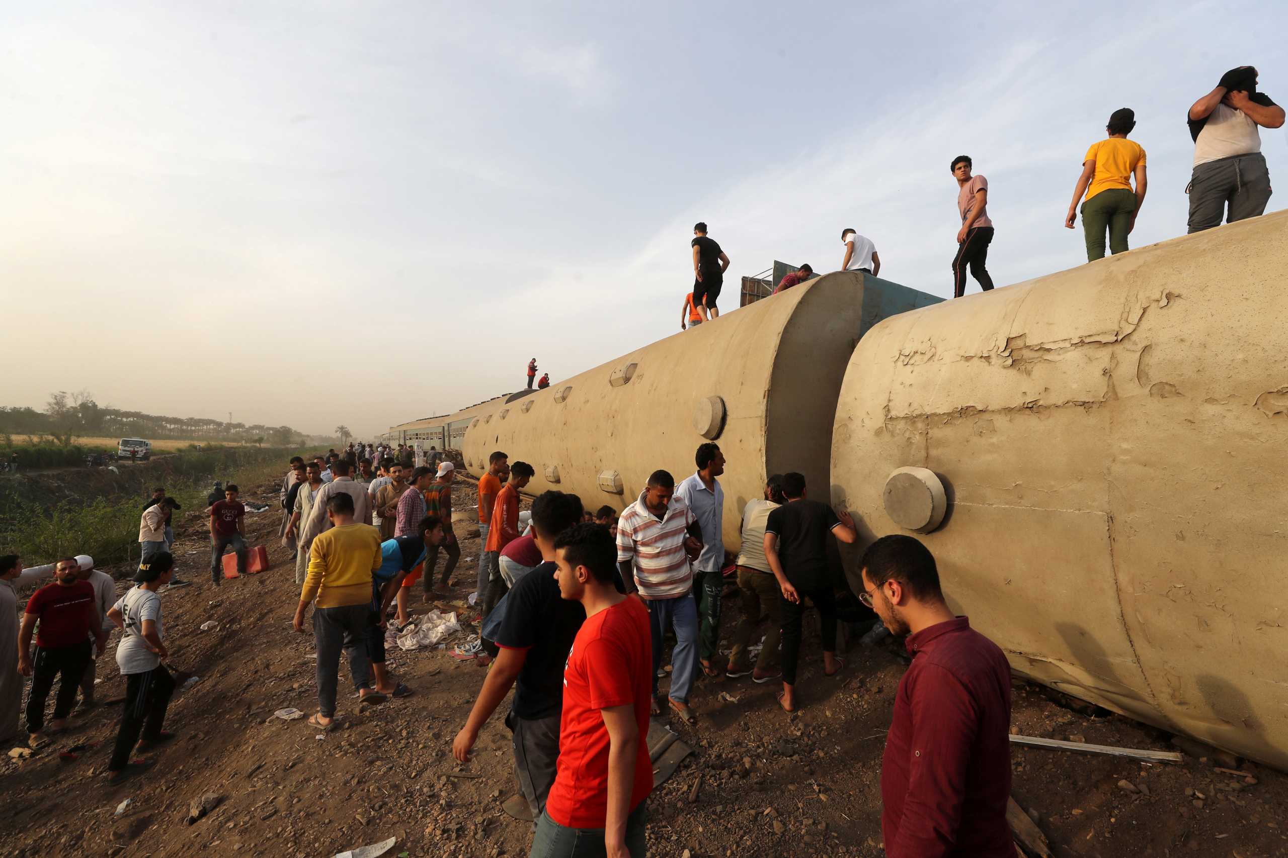 People gather at the site where train carriages derailed in Qalioubia province, north of Cairo, Egypt April 18, 2021. REUTERS