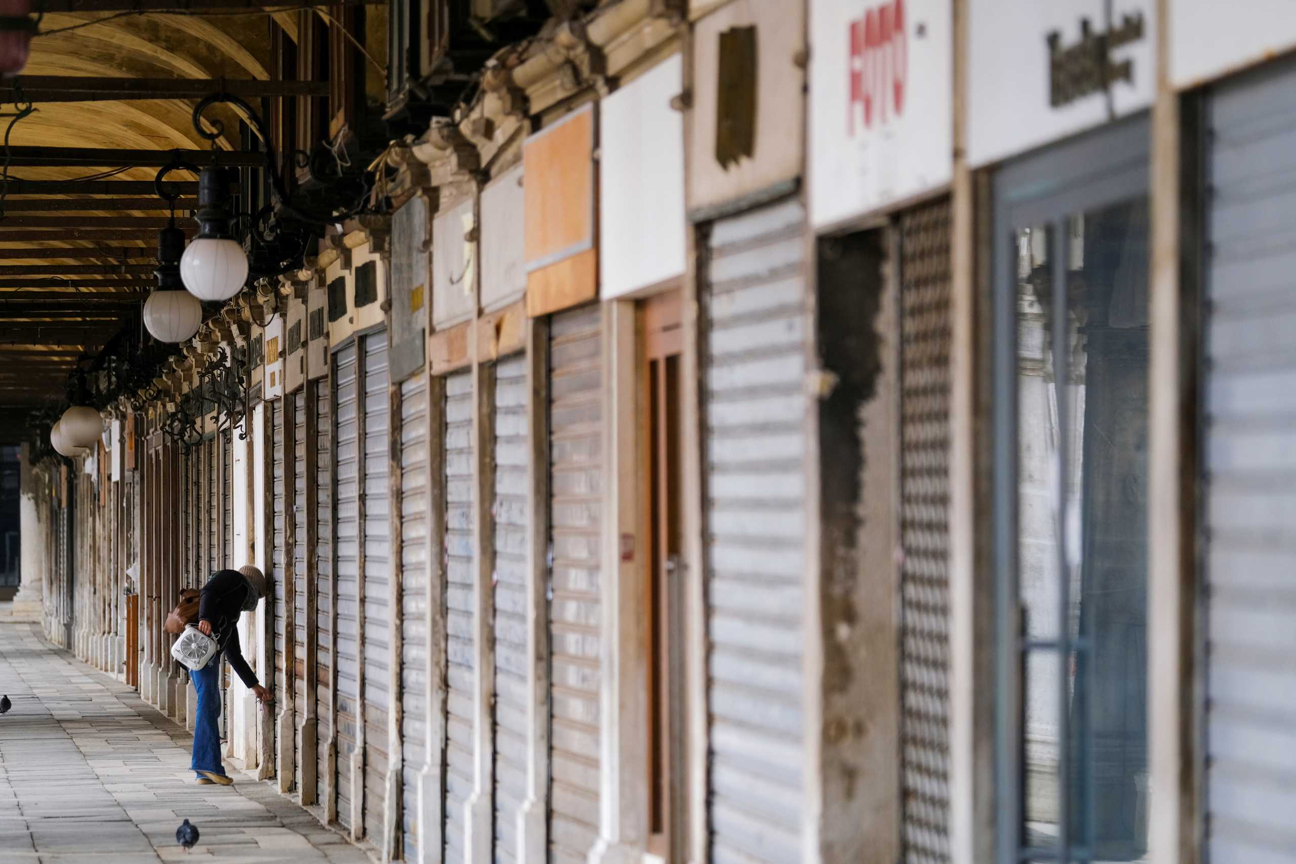 A woman closes a shop in St. Mark's Square as the region of Veneto becomes a 'red zone', going into lockdown in an effort to reduce coronavirus disease (COVID-19) infections in the country, in Venice, Italy, March 15, 2021. REUTERS