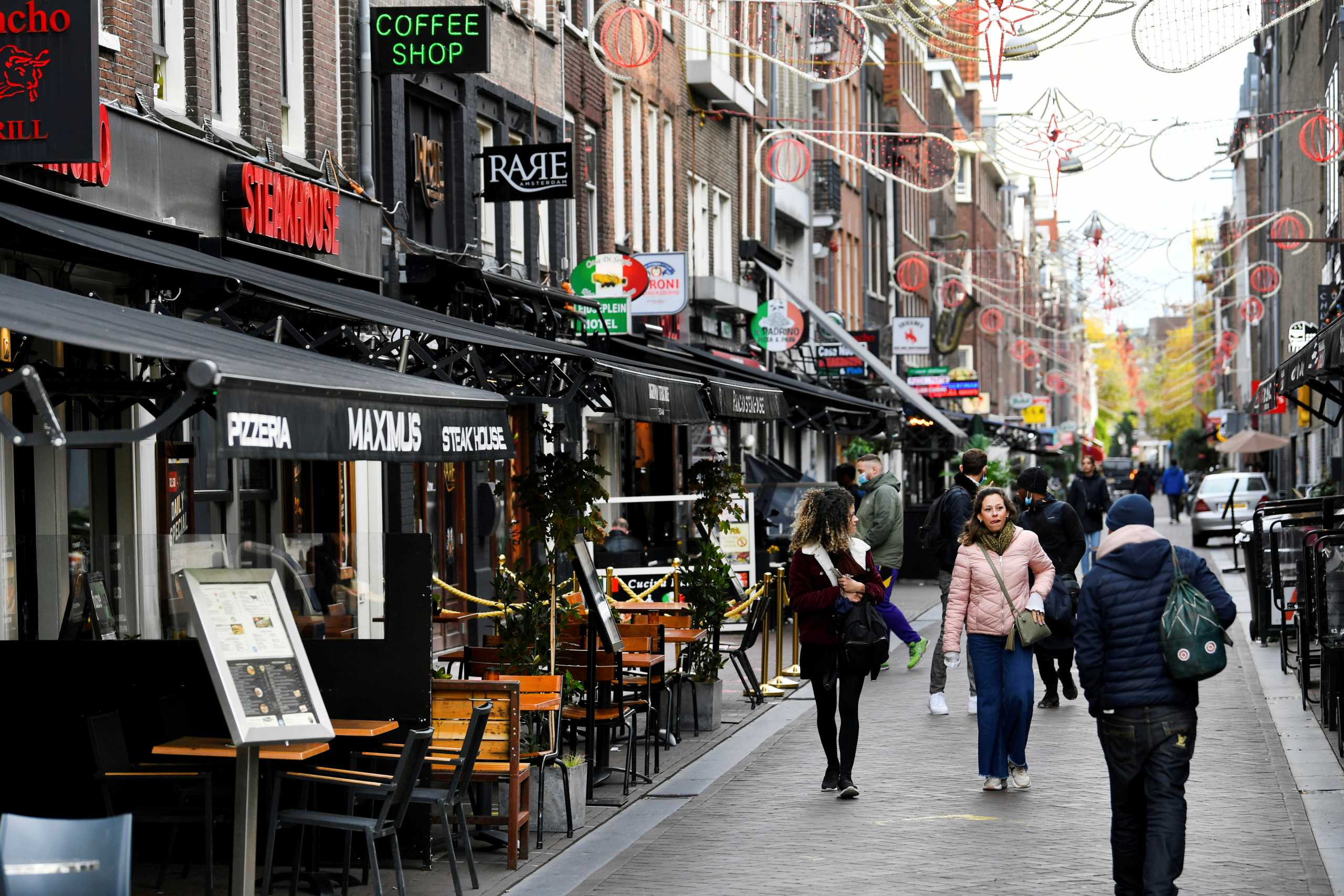 FILE PHOTO: People walk past restaurants and bars following the new social restrictions announced by the Dutch government, as the Netherlands battle to control the spread of the coronavirus disease (COVID-19), in Amsterdam, Netherlands October 14 2020. REUTERS