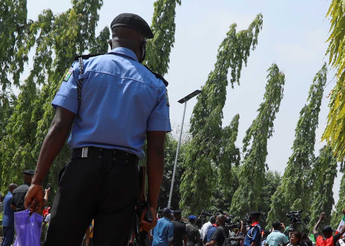 A police officer carries a bag with smoke gas canisters while members of the Nigeria Labour Congress attend a protest rally at the National Assembly Abuja, Nigeria March 10, 2021. REUTERS