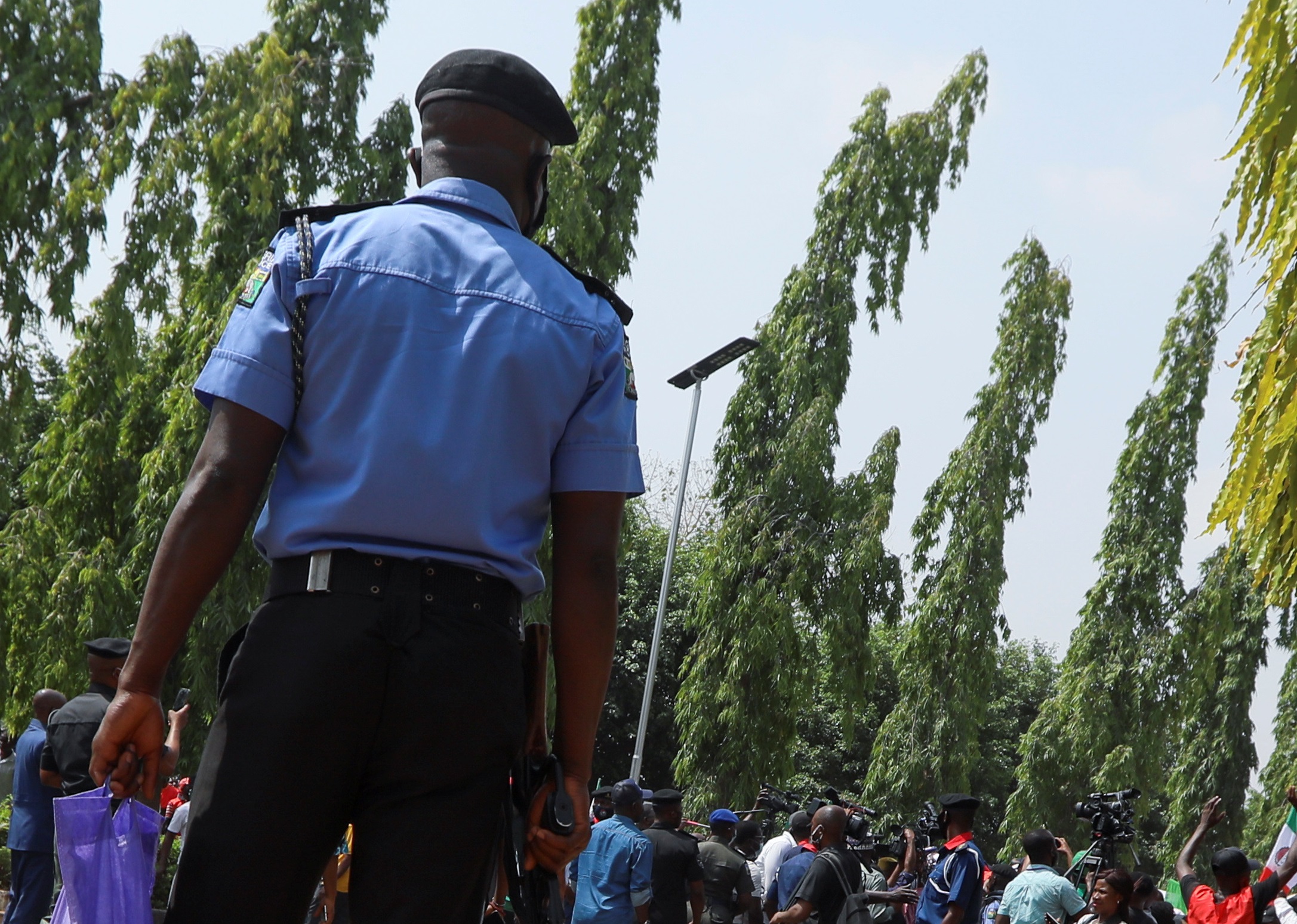 A police officer carries a bag with smoke gas canisters while members of the Nigeria Labour Congress attend a protest rally at the National Assembly Abuja, Nigeria March 10, 2021. REUTERS