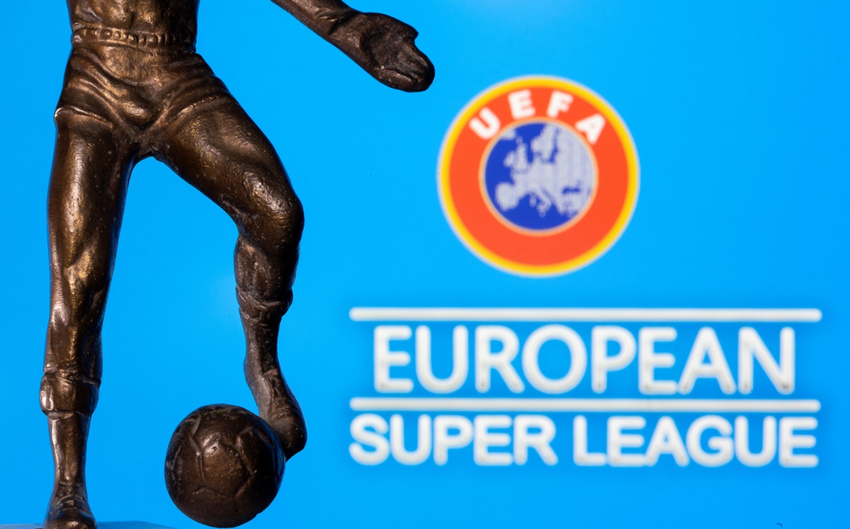 A metal figure of a football player with a ball is seen in front of the words "European Super League" and the UEFA logo in this illustration taken April 20, 2021. REUTERS