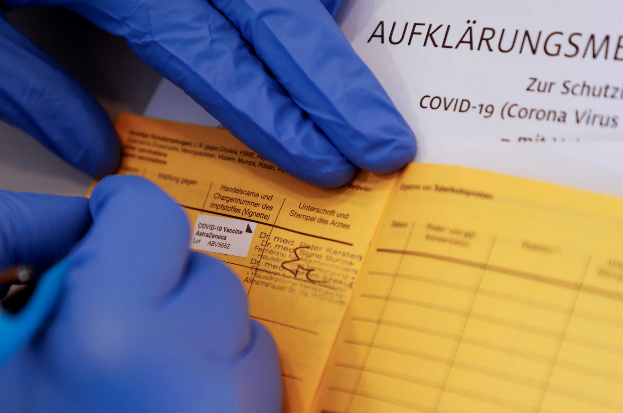 General practitioner Kerem Erekul fills in the vaccination certificate after a man received a dose of the AstraZeneca coronavirus disease (COVID-19) vaccine in a doctor's practice in Berlin, Germany, April 10, 2021.     REUTERS