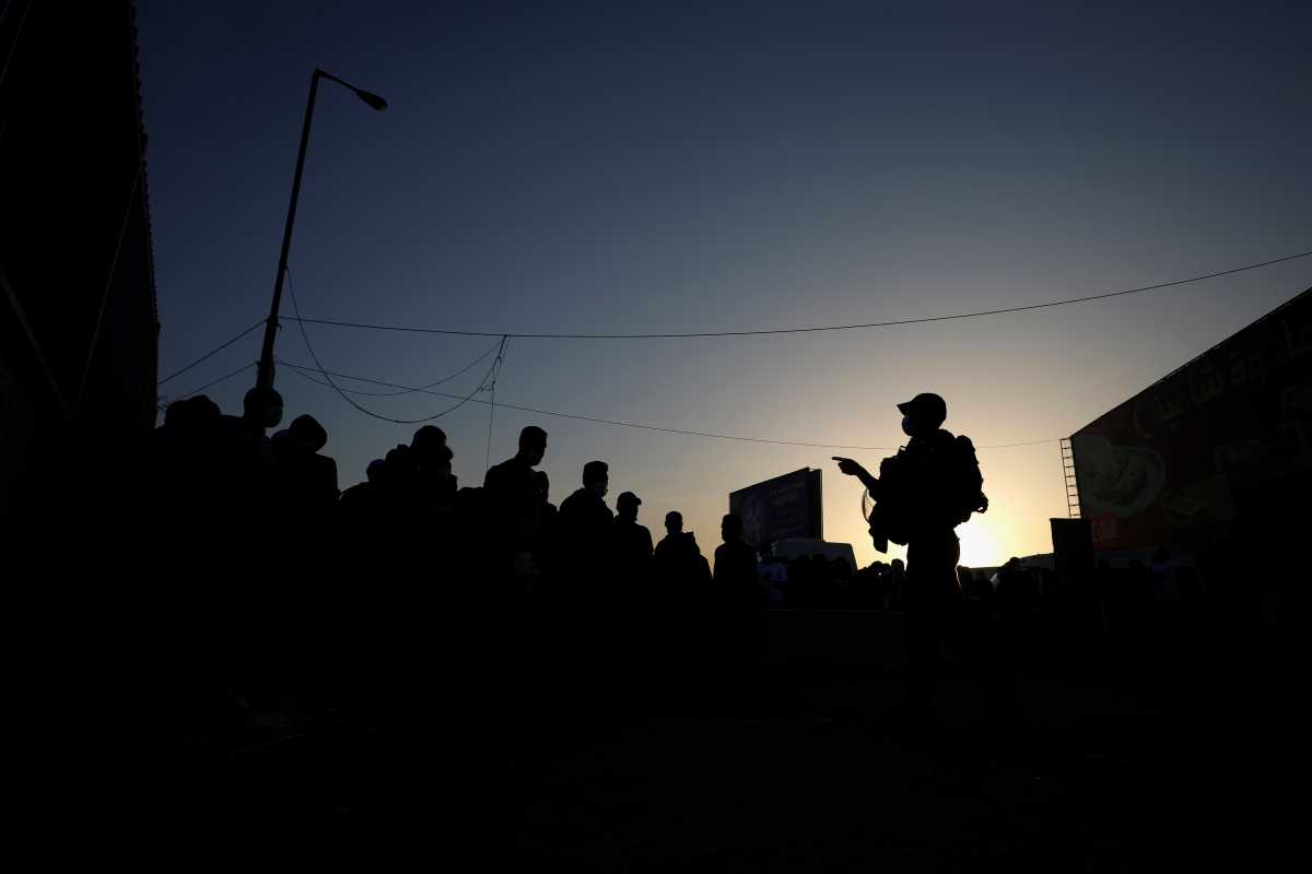 An Israeli border police member gestures as Palestinians make their way through Israeli Qalandia checkpoint to attend the first Friday prayers of the holy fasting month of Ramadan in Jerusalem's Al-Aqsa mosque, near Ramallah in the occupied West Bank April 16, 2021. REUTERS