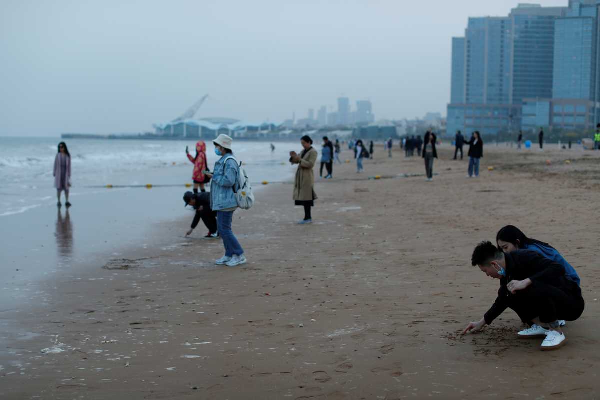 People enjoy the beach, following an oil spill in the Yellow Sea caused by a collision between tanker A Symphony and bulk vessel Sea Justice off Qingdao port, in Qingdao, Shandong province, China, April 28, 2021. REUTERS