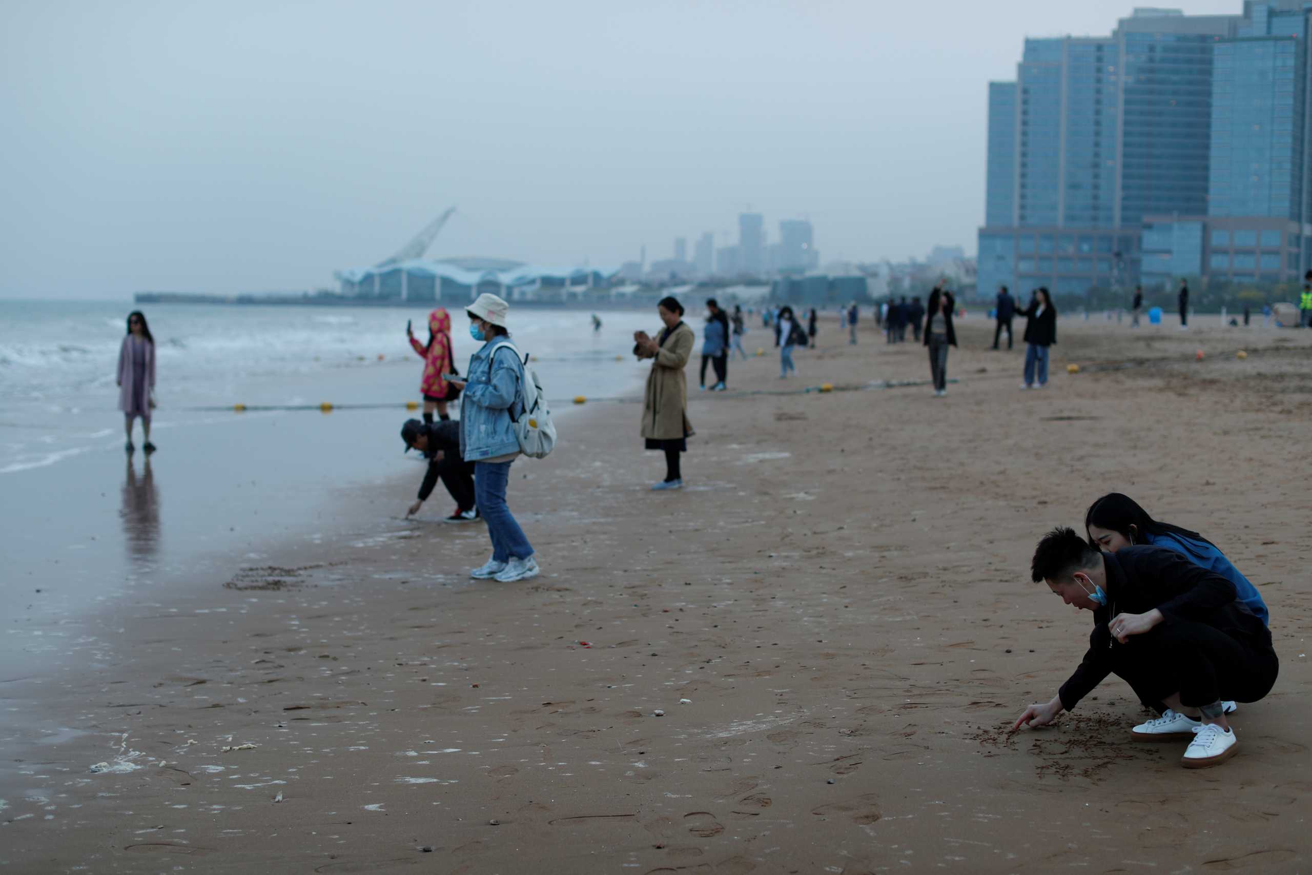 People enjoy the beach, following an oil spill in the Yellow Sea caused by a collision between tanker A Symphony and bulk vessel Sea Justice off Qingdao port, in Qingdao, Shandong province, China, April 28, 2021. REUTERS