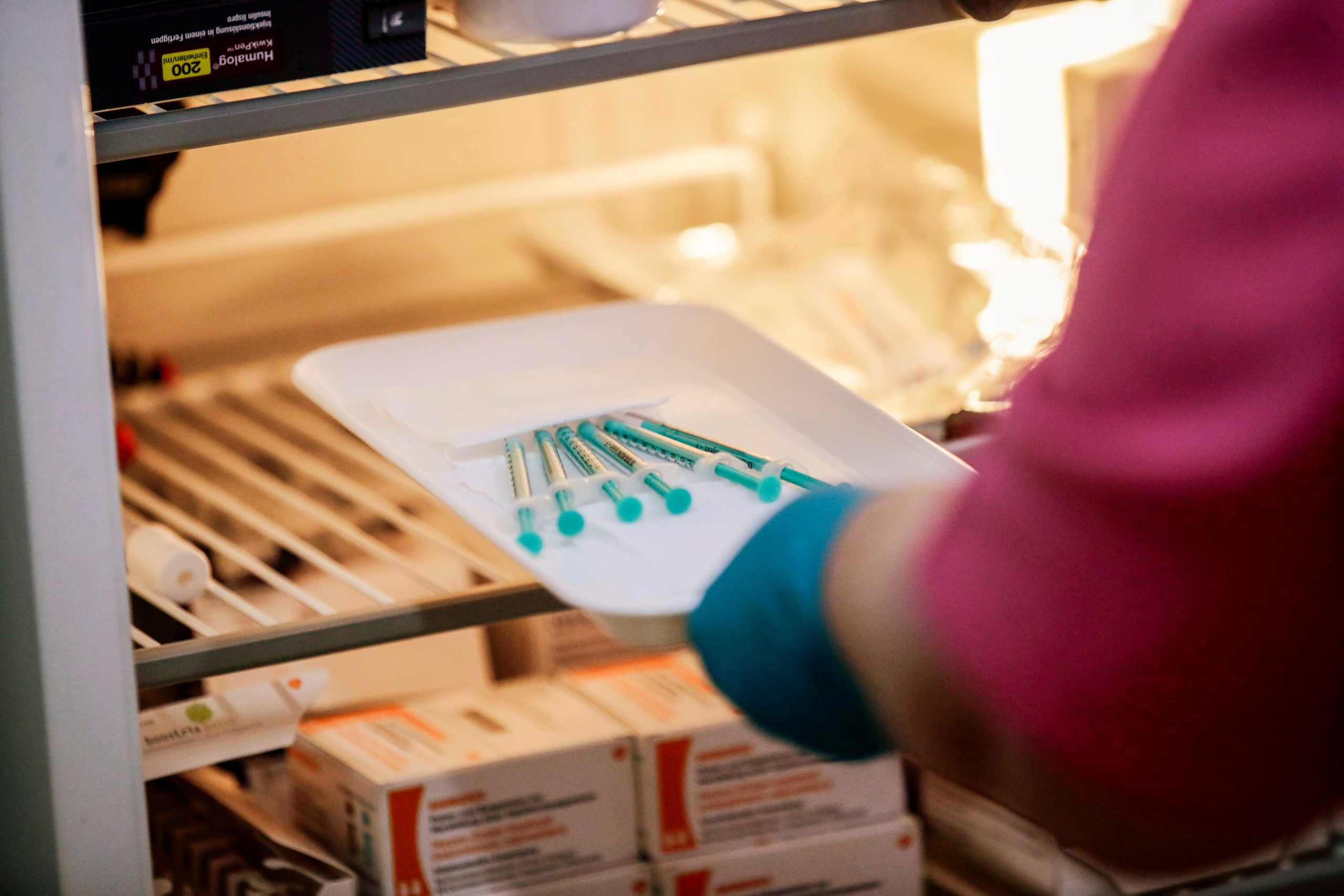 A healthcare worker takes syringes with Pfizer-BioNTech coronavirus disease (COVID-19) vaccine  out of a fridge in a doctors' practice in Berlin, Germany, April 7, 2021. REUTERS