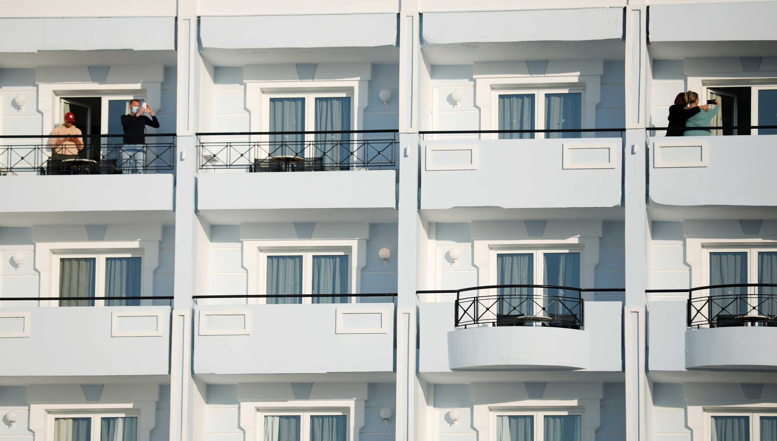 Dutch tourists, who will spend a week long holiday in isolation as part of an experiment, stand on their balconies at the a tourist resort the Mitsis Grand Hotel Beach, amid the coronavirus disease (COVID-19) outbreak on the island of Rhodes, Greece April 12, 2021. REUTERS