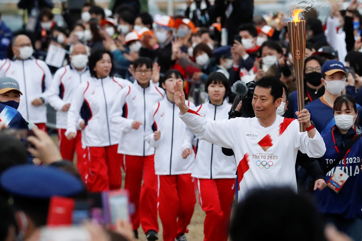 Yoshihide Muroya, Japanese aerobatics pilot and race pilot of the Red Bull Air Race World Championship, reacts as he carries the Olympic torch at Hibarigahara Festival Site, during the last leg of the first day of the Tokyo 2020 Olympic torch relay, in Minamisoma, Fukushima prefecture, Japan, March 25, 2021.  REUTERS