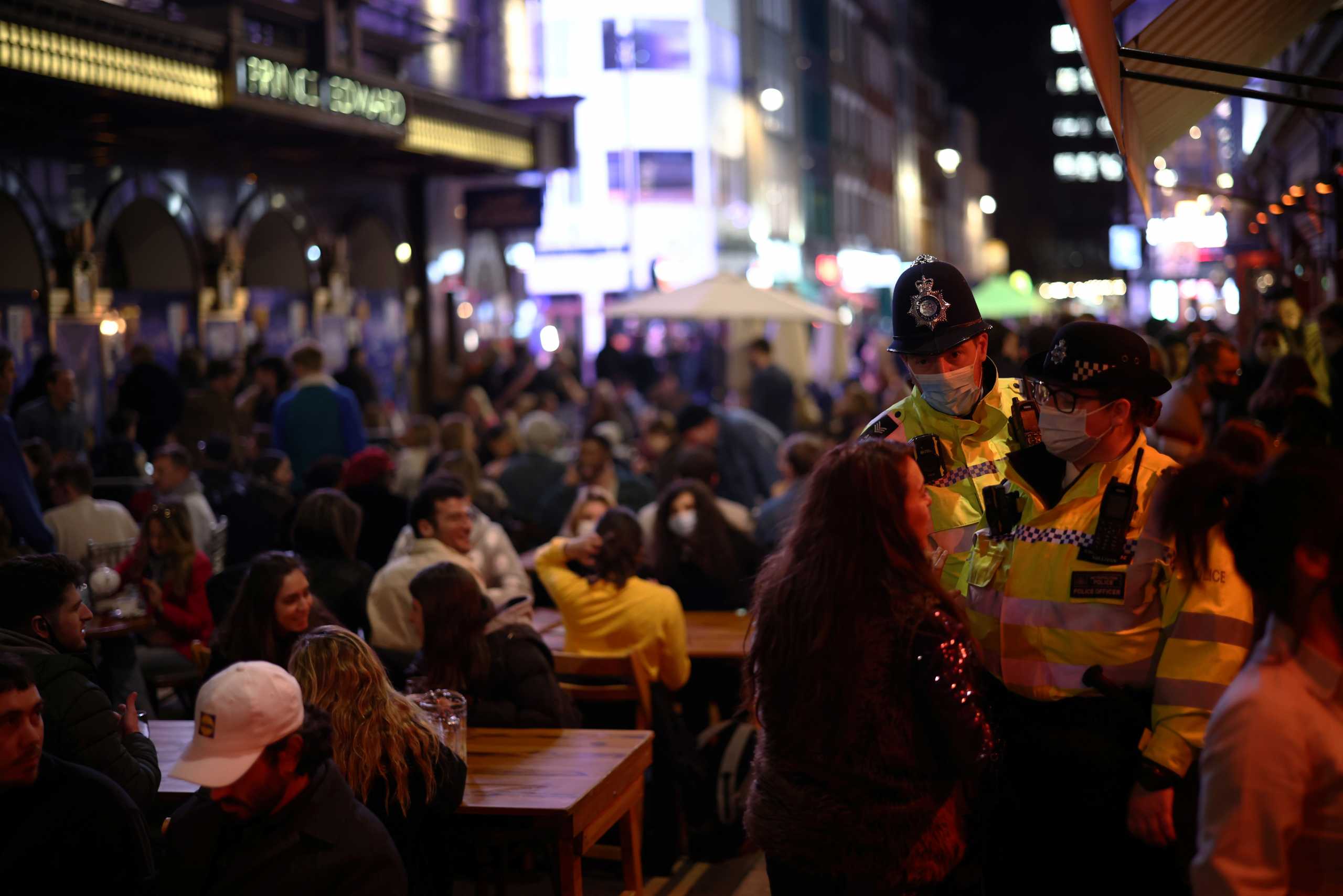 A woman speaks with the Metropolitan Police officers as people enjoy the evening at an outside restaurant area in Soho, as the coronavirus disease (COVID-19) restrictions ease, in London, Britain April 12, 2021. REUTERS