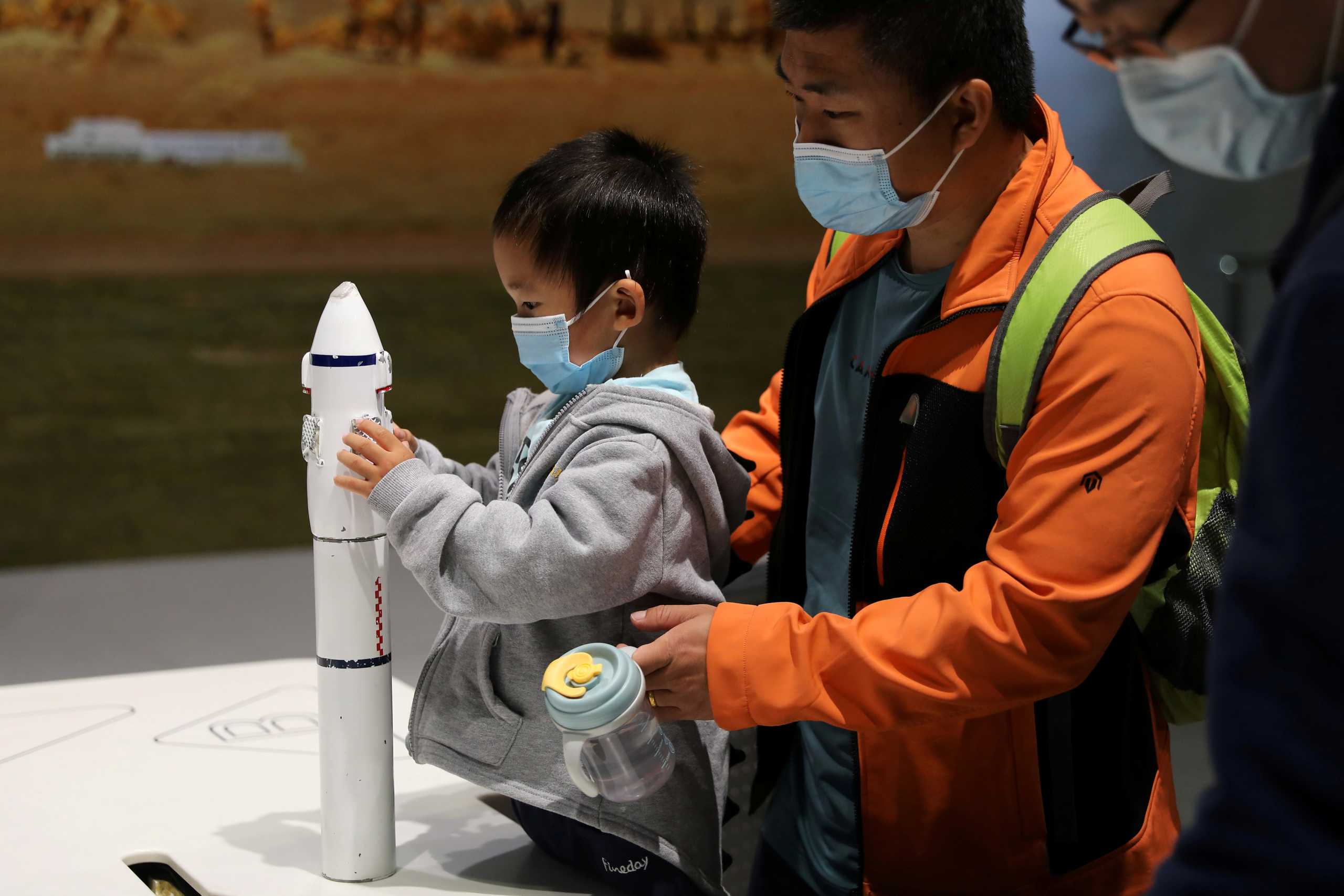 FILE PHOTO: A child holds part of a rocket model at an exhibition featuring the development of China's space exploration on the country's Space Day at China Science and Technology Museum in Beijing, China April 24, 2021. REUTERS