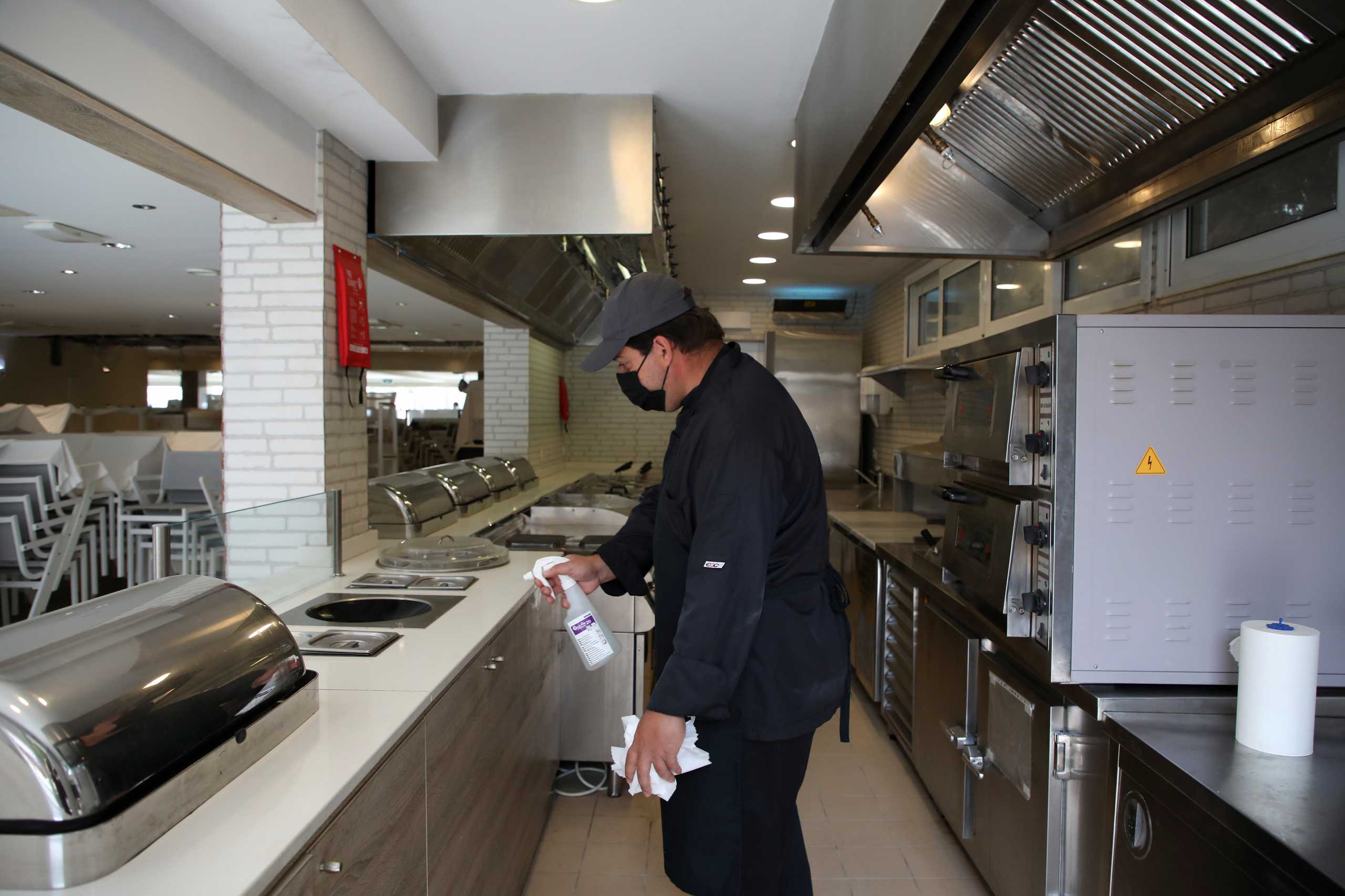 A worker wearing a protective face mask cleans the counter along the buffet line at the Sun Beach Resort, amid the coronavirus disease (COVID-19) pandemic, on the island of Rhodes, Greece, April 14, 2021. Picture taken April 14, 2021. REUTERS