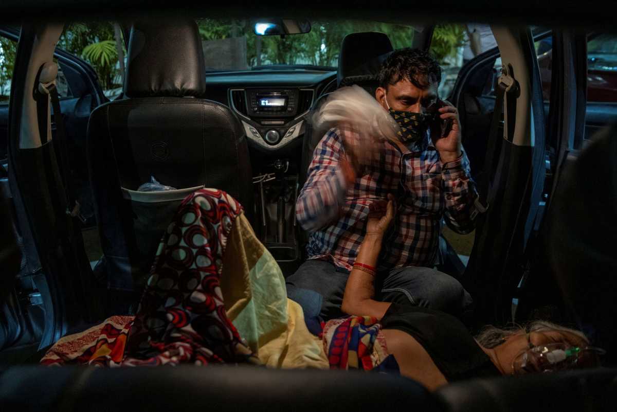 Manoj Kumar sits next to his mother, Vidhya Devi, who was suffering from a breathing problem as she receives oxygen support for free inside her car at a Gurudwara (Sikh temple), amidst the spread of the coronavirus disease (COVID-19), in Ghaziabad, India, April 24, 2021. Picture taken April 24, 2021. REUTERS
