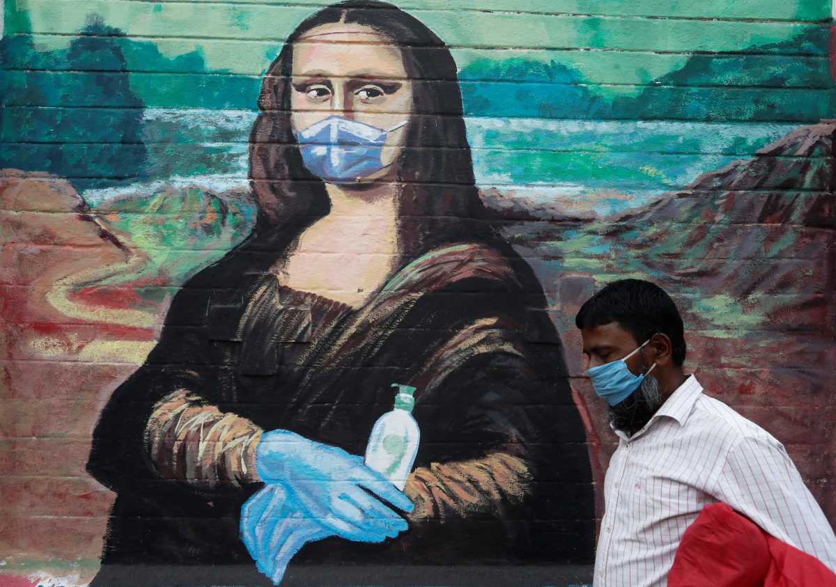 A man wearing a protective face mask walks past a graffiti depicting Mona Lisa wearing a mask, gloves and holding a sanitiser bottle, amidst the spread of the coronavirus disease (COVID-19), on a street in Mumbai, India, March 30, 2021. REUTERS