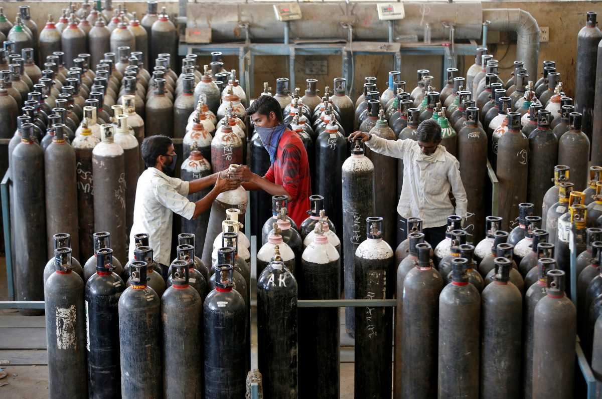 People carry oxygen cylinders after refilling them in a factory, amidst the spread of the coronavirus disease (COVID-19) in Ahmedabad, India, April 25, 2021. REUTERS