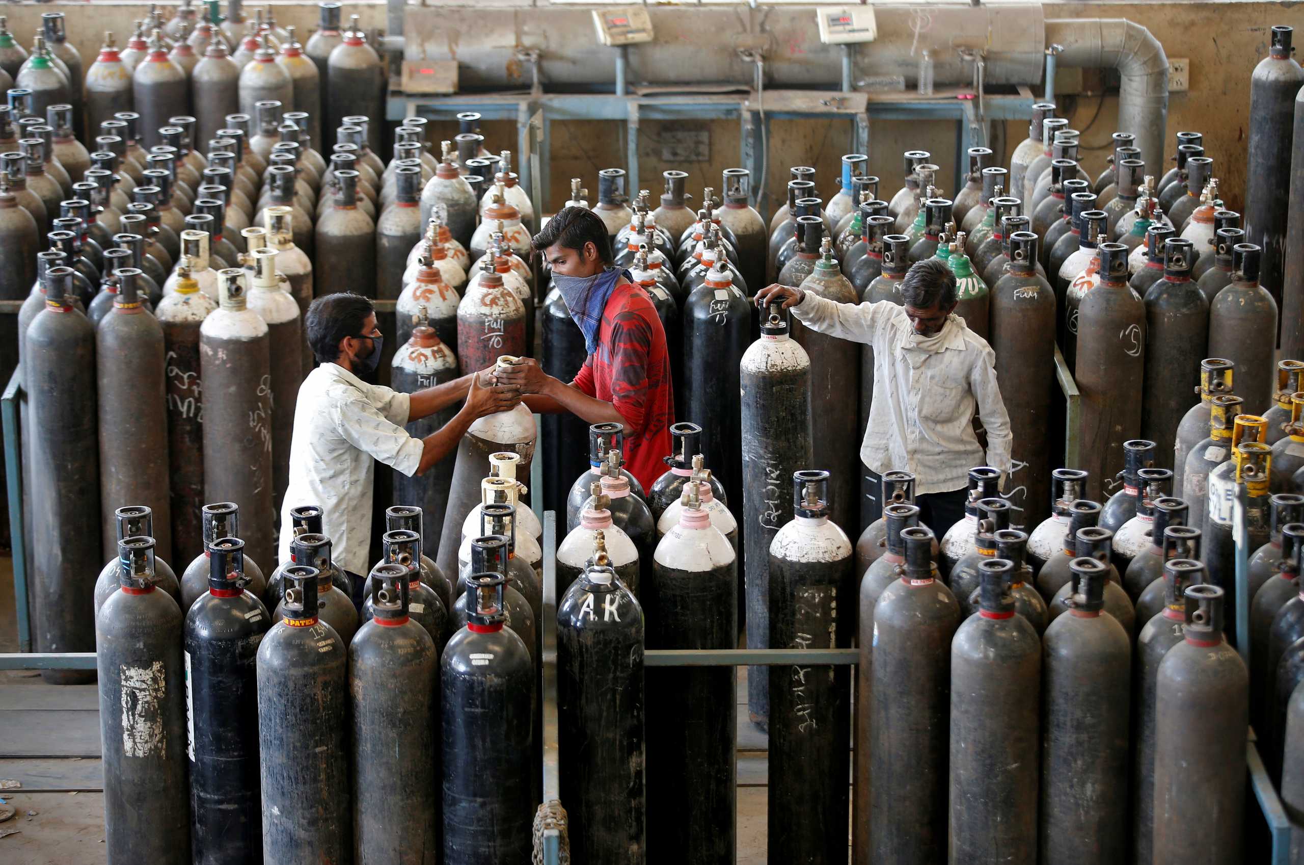 People carry oxygen cylinders after refilling them in a factory, amidst the spread of the coronavirus disease (COVID-19) in Ahmedabad, India, April 25, 2021. REUTERS