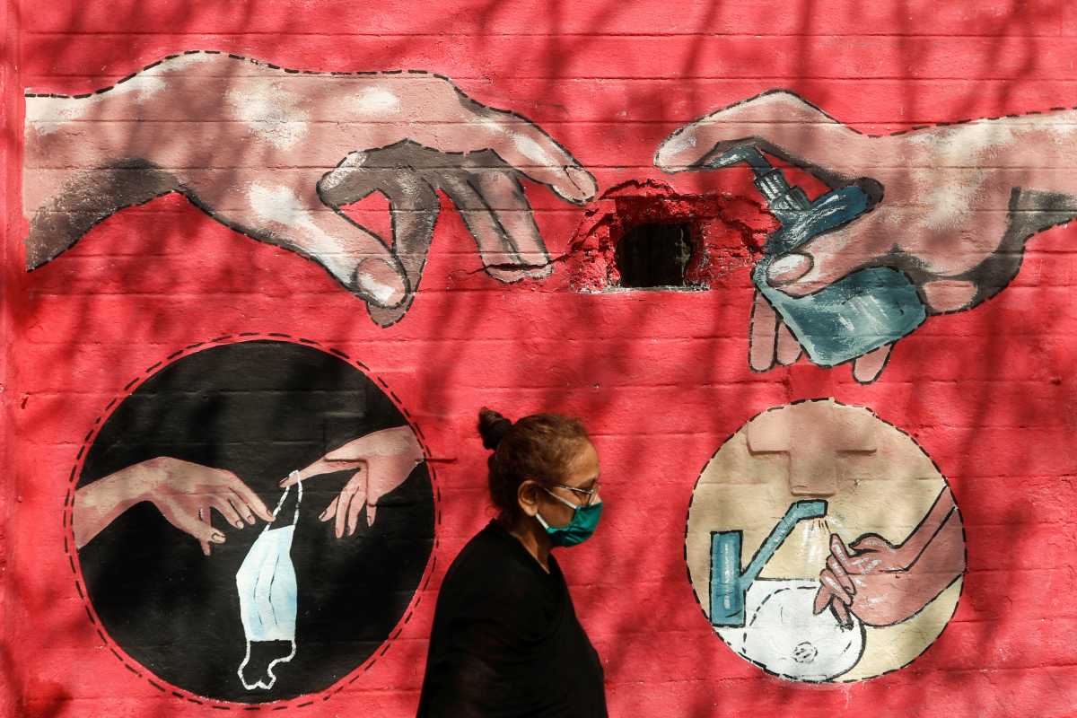 FILE PHOTO: A woman walks past a graffiti, on a street, amidst the spread of the coronavirus disease (COVID-19) in Mumbai, India, April 6, 2021. REUTERS