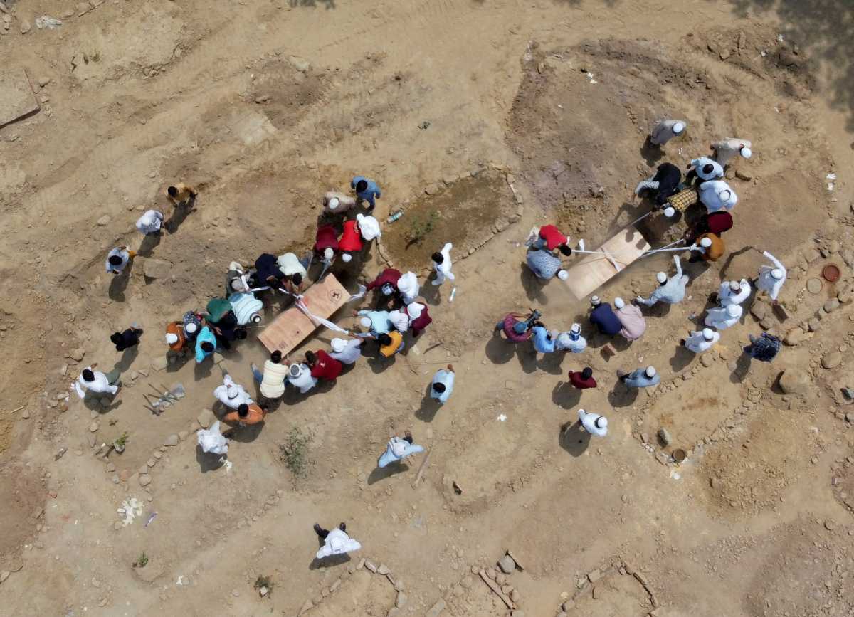 People bury the bodies of victims who died due to the coronavirus disease (COVID-19), at a graveyard in New Delhi, India, April 16, 2021. Picture taken with a drone. REUTERS