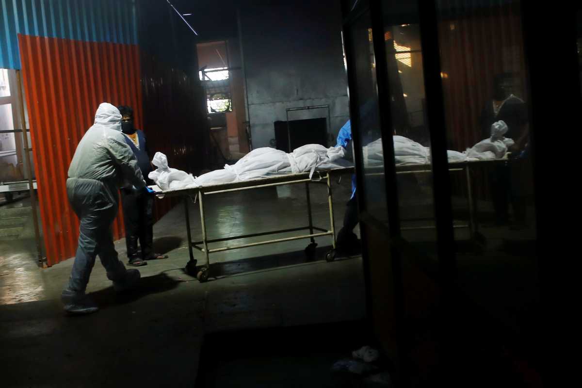 A health worker wearing personal protective equipment (PPE) carries a body of a person, who died from the coronavirus disease (COVID-19), before their cremation, at a crematorium in New Delhi, India April 24, 2021. REUTERS
