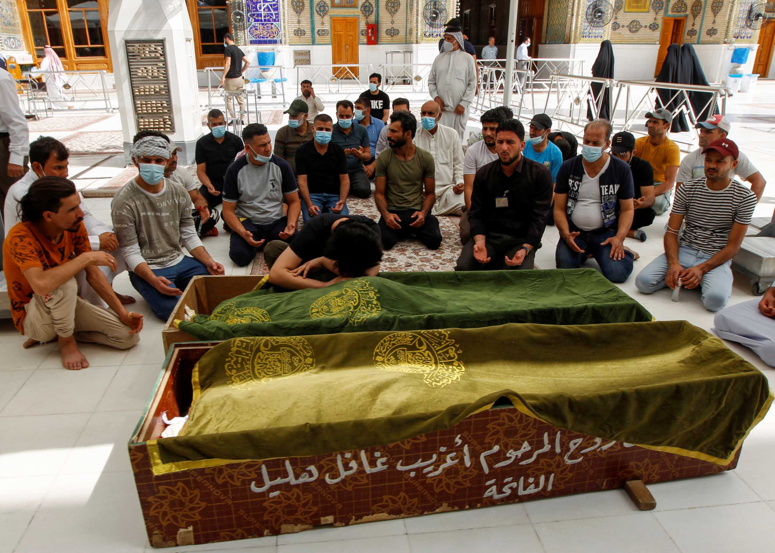 Mourners pray next to the coffins of people who were killed in a fire at a hospital in southeastern Baghdad that had been equipped to house COVID-19 patients, in Najaf, Iraq, April 25, 2021. REUTERS