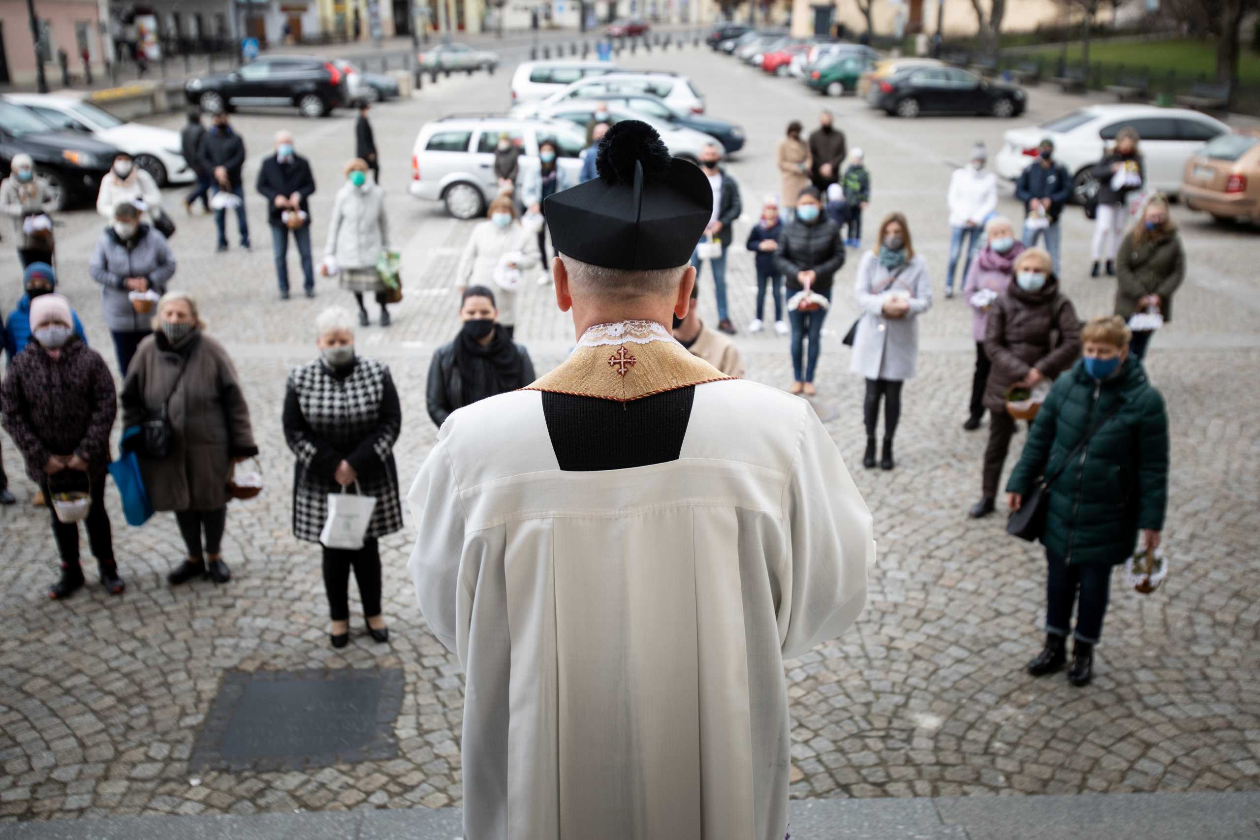 A priest blesses as Catholic believers wearing protective masks take part in the traditional blessing of the Easter food baskets on Holy Saturday, as the spread of coronavirus disease (COVID-19) outbreak continues, outside of the church in Lublin, Poland April 3, 2021. Jakub Orzechowski