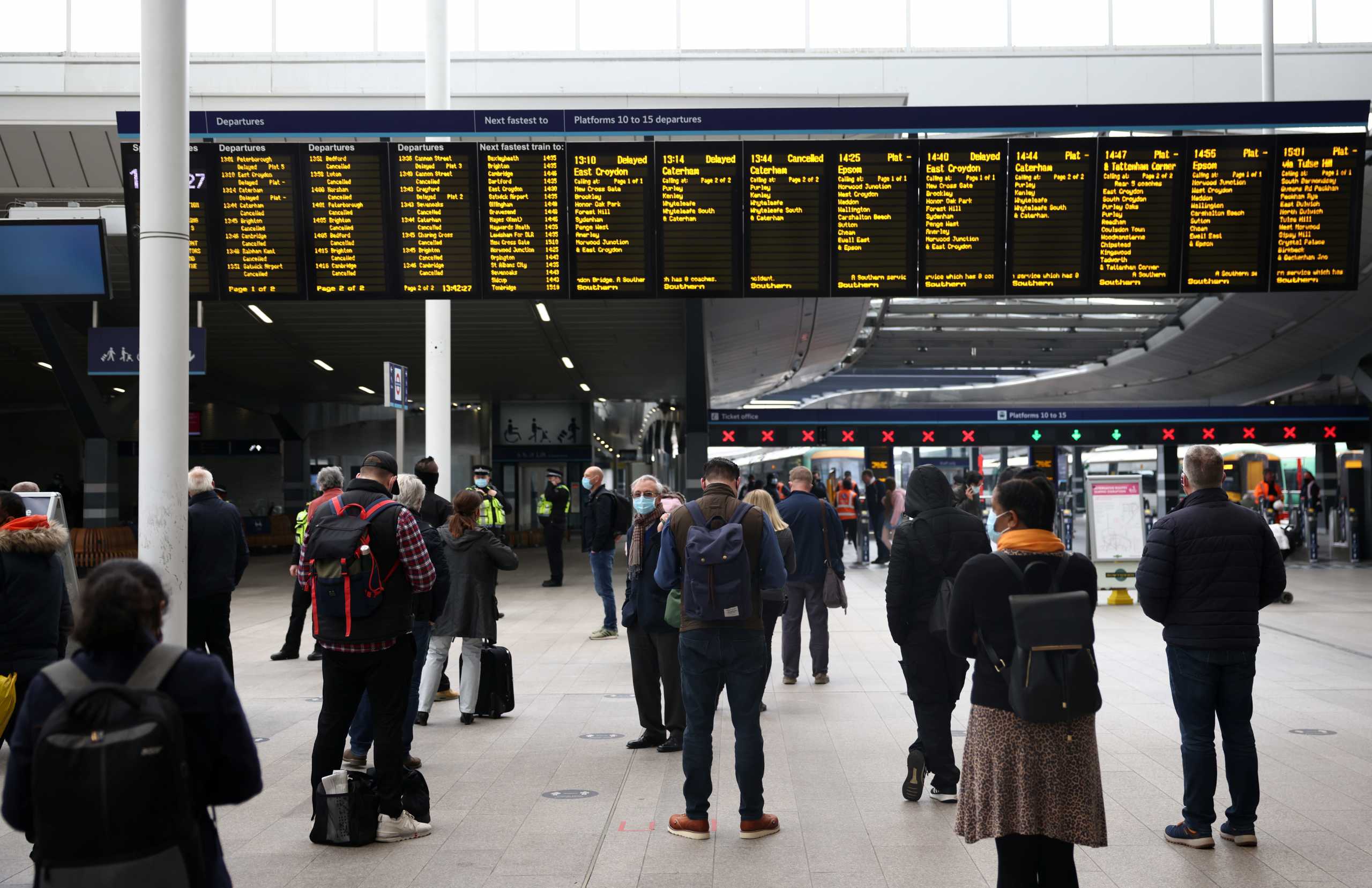 People wait in front of closed platforms at London Bridge station after it was evacuated following a security alert, in London, Britain April 21, 2021. REUTERS