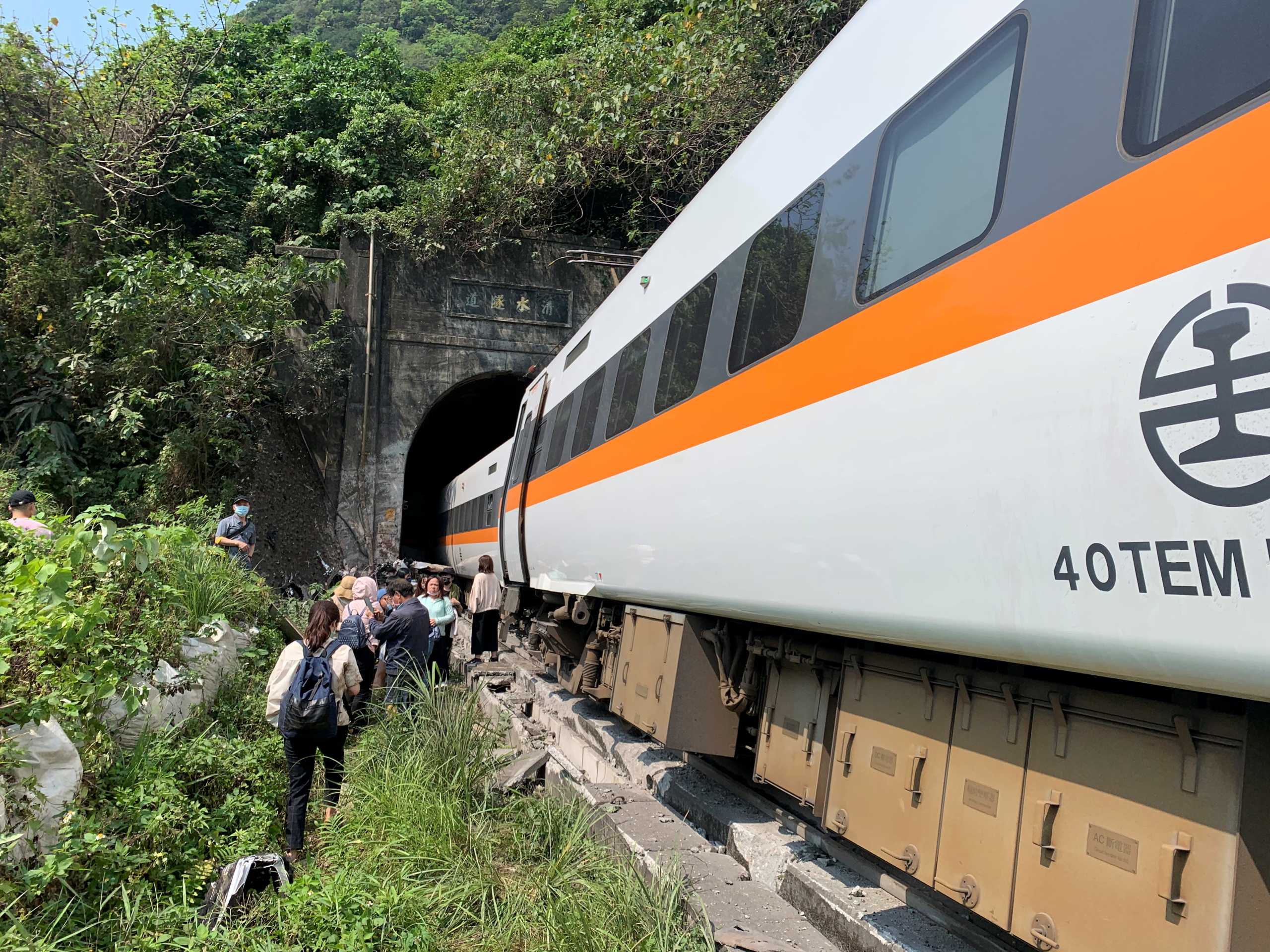 People walk next to a train which derailed in a tunnel north of Hualien, Taiwan April 2, 2021, in this handout image provided by Taiwan's National Fire Agency. Taiwan's National Fire Agency
