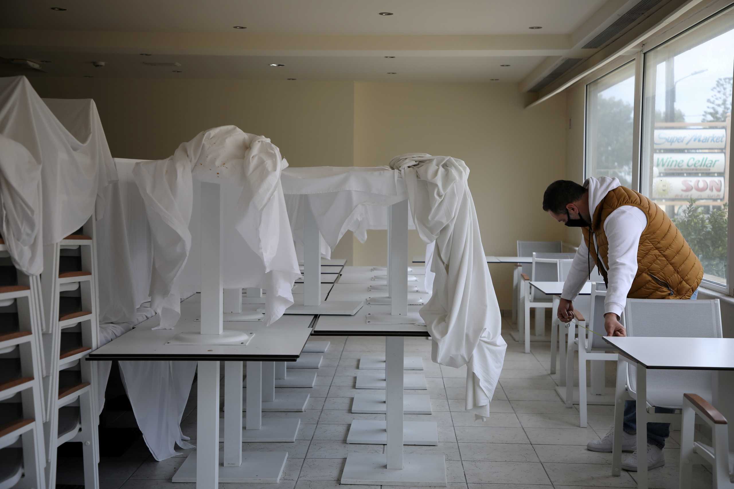 FILE PHOTO: A staff member, wearing a protective mask due to the coronavirus disease (COVID-19) pandemic, measures the distance between the tables and the chairs according to the safety guidelines inside a dining room at the Sun Beach Resort on the island of Rhodes, Greece, April 14, 2021. REUTERS