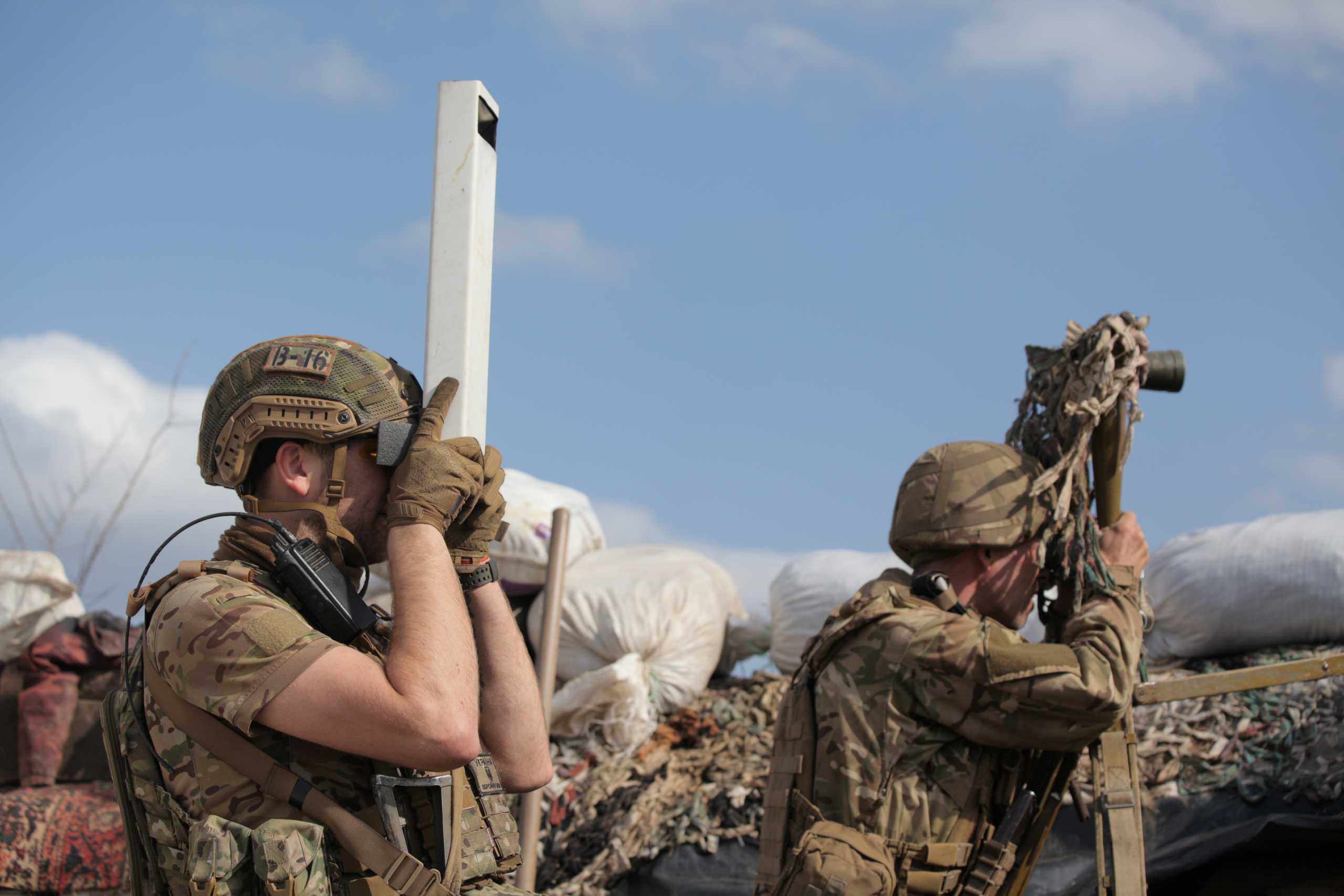 Service members of the Ukrainian armed forces use periscopes while observing the area at fighting positions on the line of separation near the rebel-controlled city of Donetsk, Ukraine April 7, 2021. REUTERS