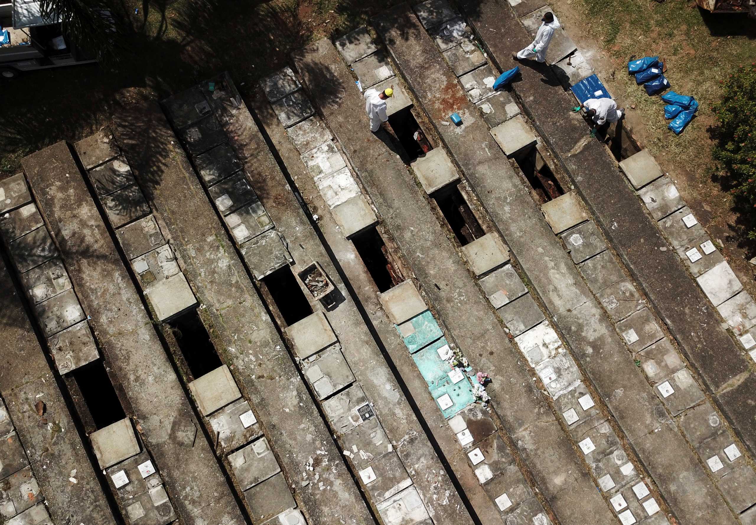 Aerial view of gravediggers wearing protective suits as they perform exhumations to open space on cement graves as new burials are suspended, except private deposits and children, at Vila Nova Cachoeirinha cemetery amid the outbreak of the coronavirus disease (COVID-19) in Sao Paulo, Brazil, April 1, 2021. Picture taken with a drone. REUTERS