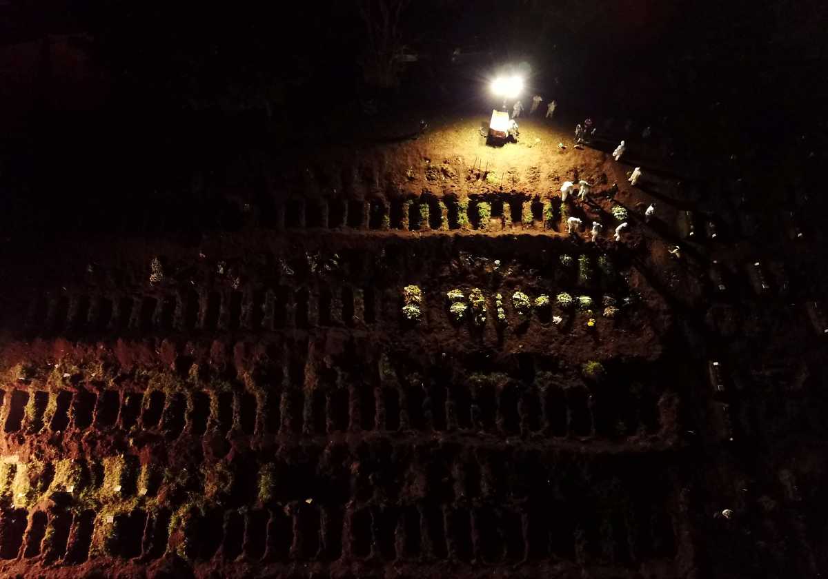 FILE PHOTO: Drone footage shows gravediggers wearing protective suits burying a coffin as spotlights illuminate the graves during night burials amid the coronavirus disease (COVID-19) at Vila Formosa cemetery in Sao Paulo, Brazil, March 30, 2021. Picture taken March 30, 2021. Picture taken with a drone. REUTERS