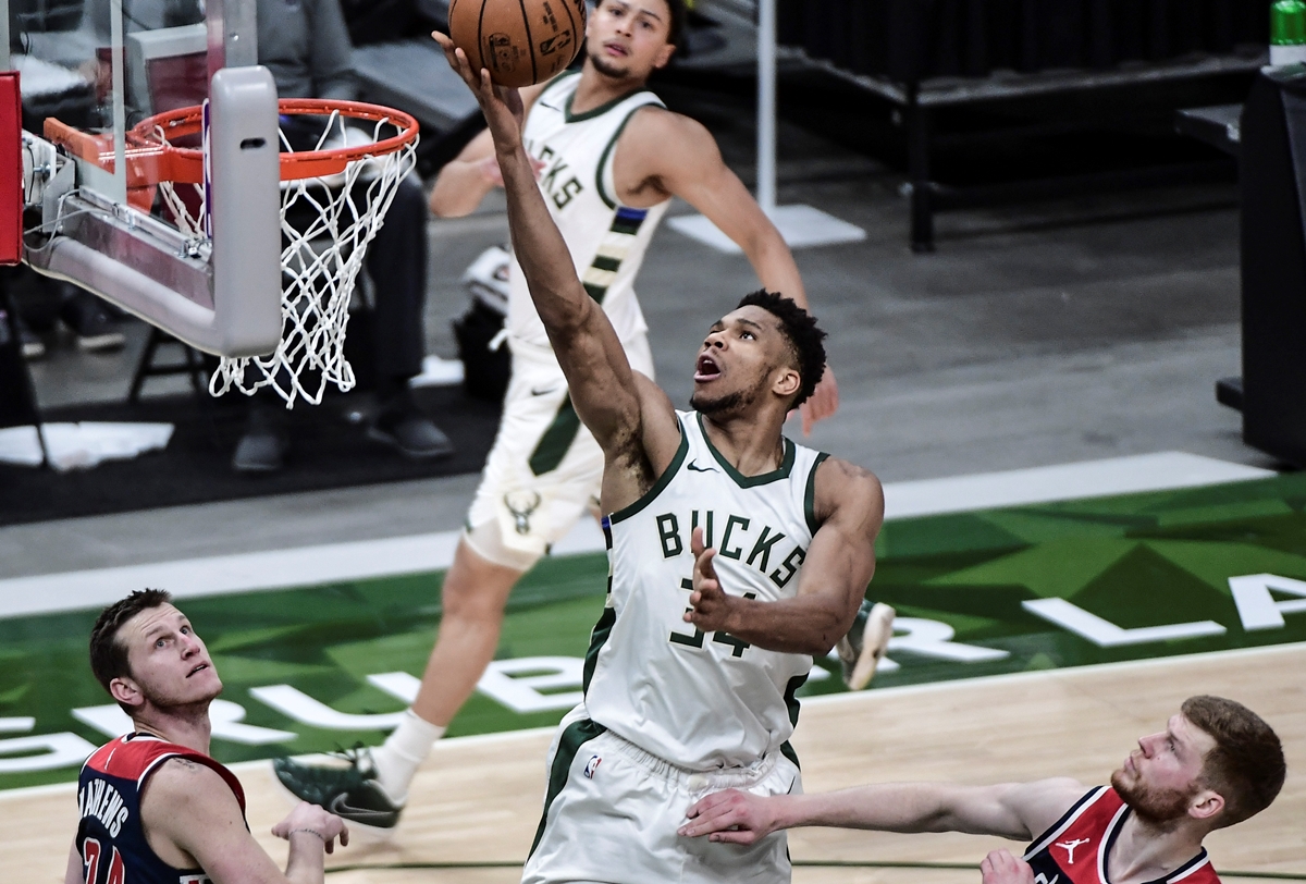 May 5, 2021; Milwaukee, Wisconsin, USA; Milwaukee Bucks forward Giannis Antetokounmpo (34) scores a basket against Washington Wizards guard Garrison Mathews (24) and forward Davis Bertans (42) in the fourth quarter at Fiserv Forum. Mandatory Credit: Benny Sieu-USA TODAY Sports