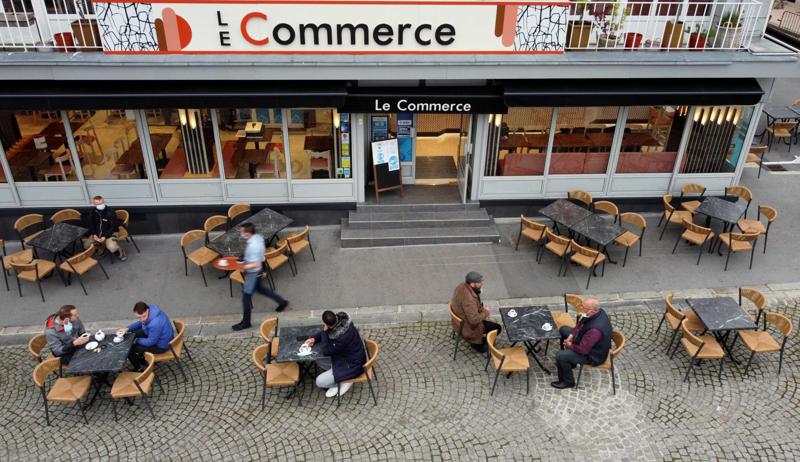 A waiter serves customers as cafes, bars and restaurants reopen their terraces in Cambrai after closing down for months, amid the coronavirus disease (COVID-19) outbreak in France, May 19, 2021. Picture taken with a drone. REUTERS
