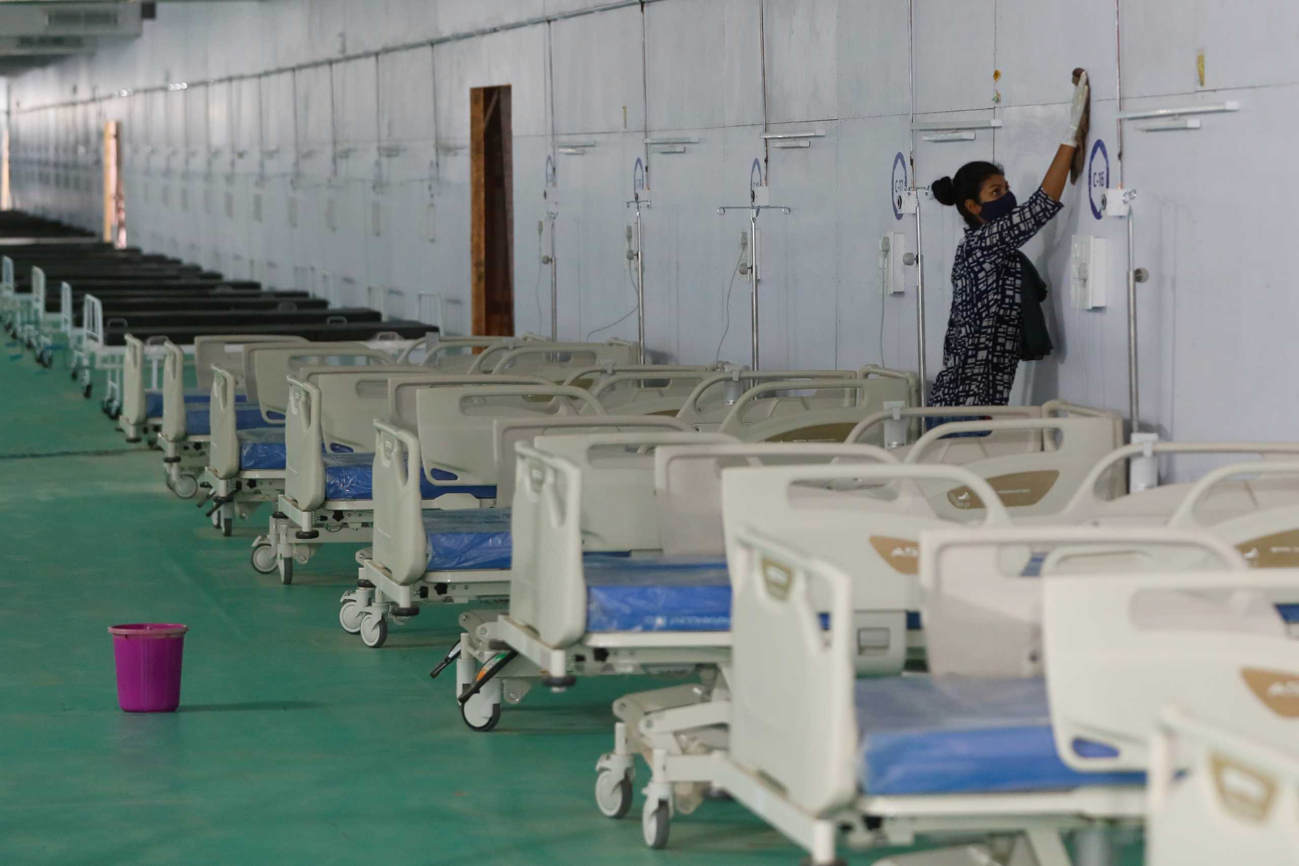 A worker cleans a wall next to beds at the site of a temporary coronavirus disease (COVID-19) care facility, at Ramlila Ground, in New Delhi, India, May 12, 2021. REUTERS