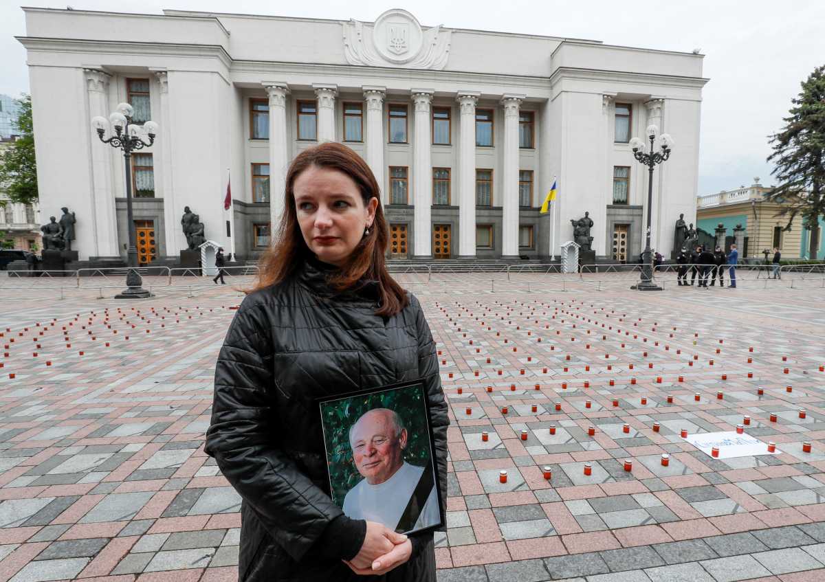A woman holds a portrait of her father near the candles commemorating 47000 victims of the coronavirus disease (COVID-19) during a protest demanding the resignation of Ukrainian Health Minister Maksym Stepanov in front of the parliament building in Kyiv, Ukraine May 17, 2021. REUTERS