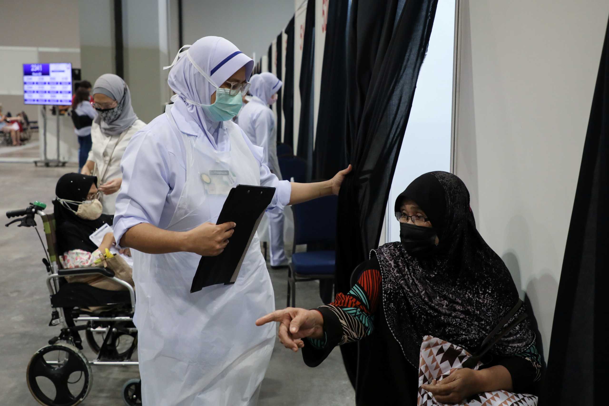 A nurse speaks to a senior citizen who waits to receive a coronavirus disease (COVID-19) vaccine, at a vaccination centre in Kuala Lumpur, Malaysia May 31, 2021. REUTERS