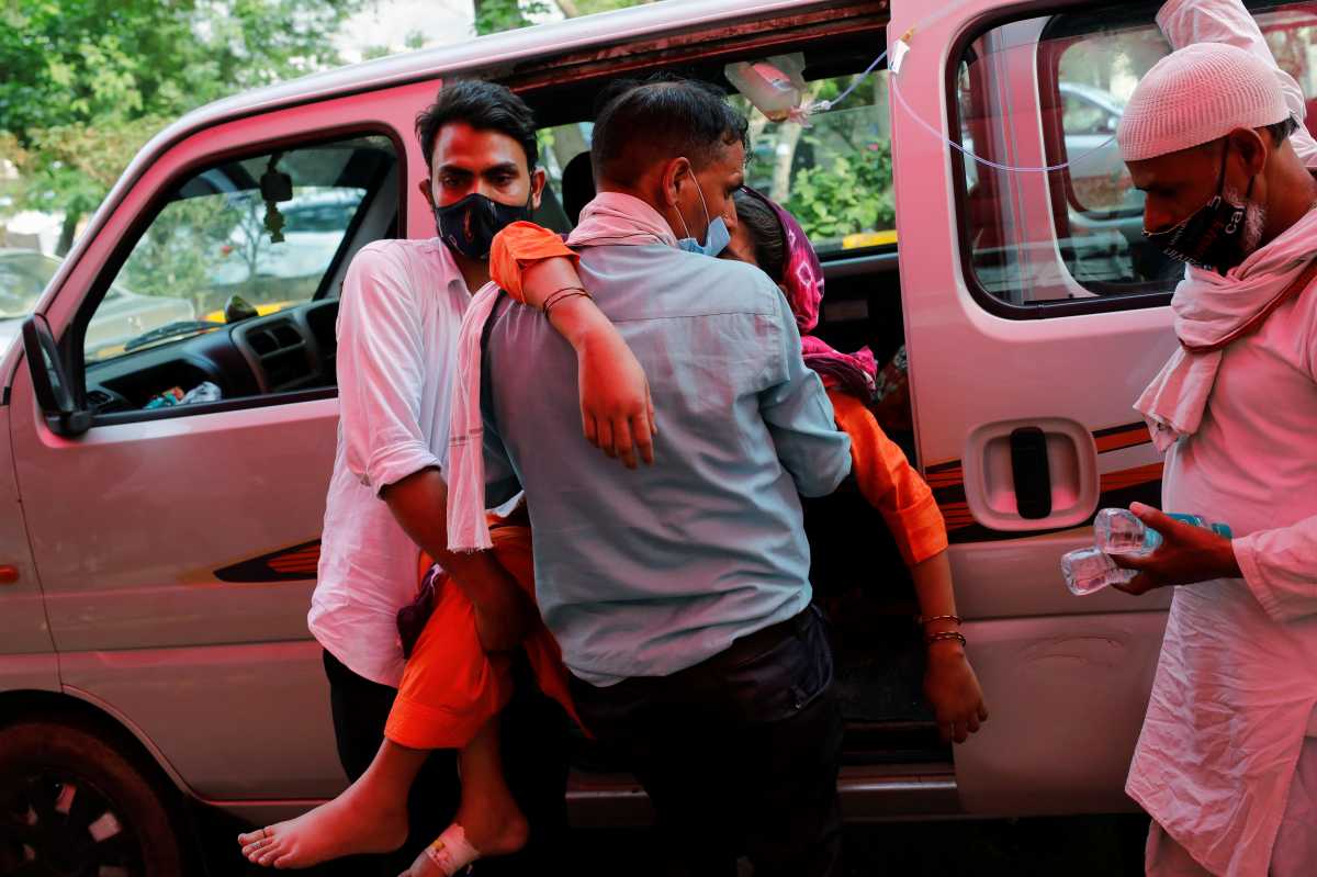 A man carries a woman, who is suffering from breathing problem, to receive oxygen support for free at a Gurudwara (Sikh temple), amidst the spread of coronavirus disease (COVID-19), in Ghaziabad, India, April 30, 2021. REUTERS