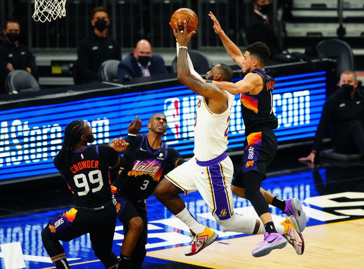 May 23, 2021; Phoenix, Arizona, USA; Los Angeles Lakers forward LeBron James (23) is fouled by Phoenix Suns guard Devin Booker (1) as he drives to the basket against Chris Paul (3) and forward Jae Crowder (99) in the second half during game one in the first round of the 2021 NBA Playoffs at Phoenix Suns Arena. Mandatory Credit: Mark J. Rebilas-USA TODAY Sports